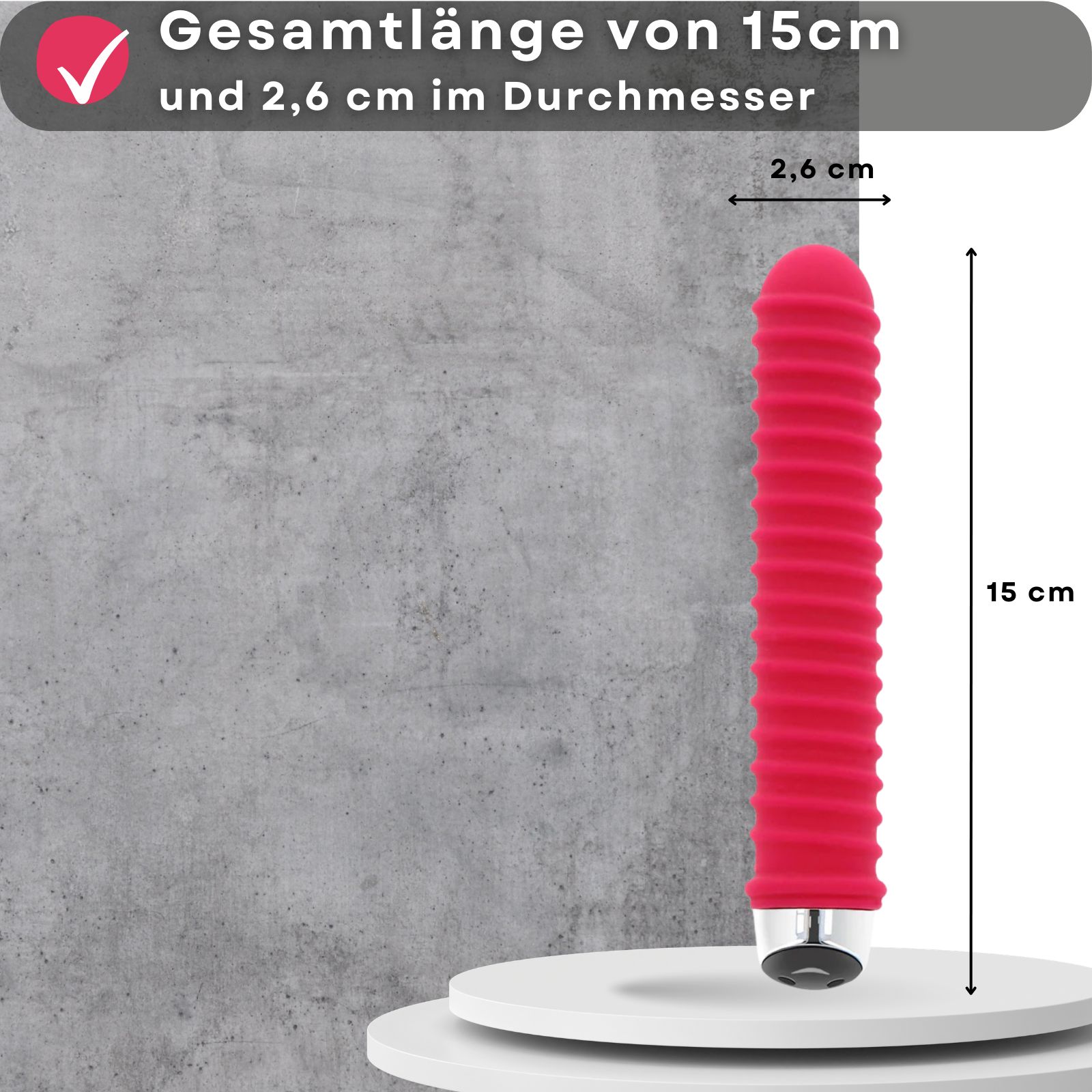 Roter Vibrator mit Rillen. Maße: 15 cm lang, 2,6 cm Durchmesser. Auf Podest.