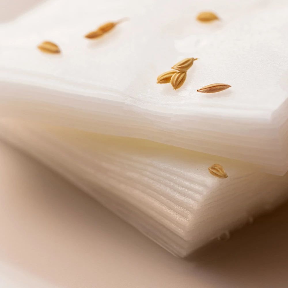 Stapel von weißen Gesichtsmasken. Einige Reiskörner liegen auf den Masken. Nahaufnahme.