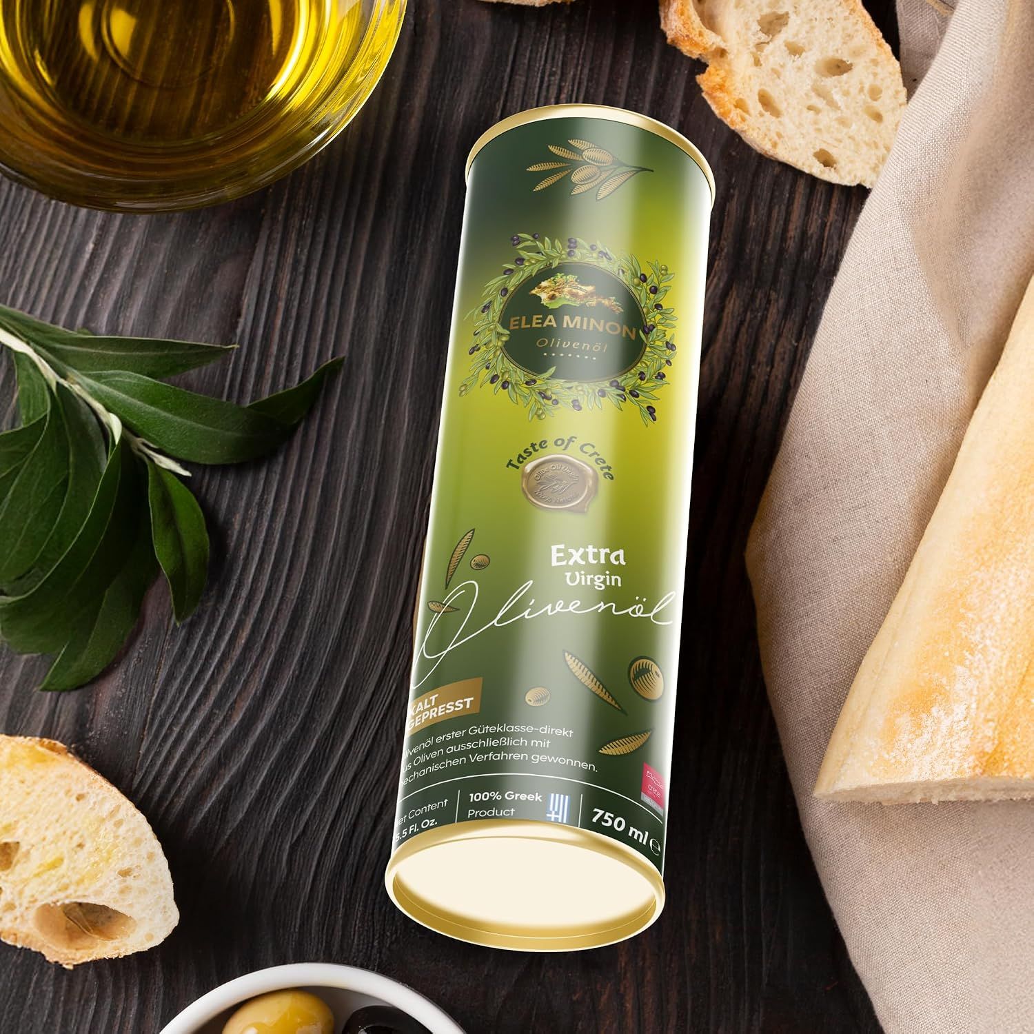 Grüner Zylinder mit Olivenöl, daneben eine Schale mit Oliven und Brot.