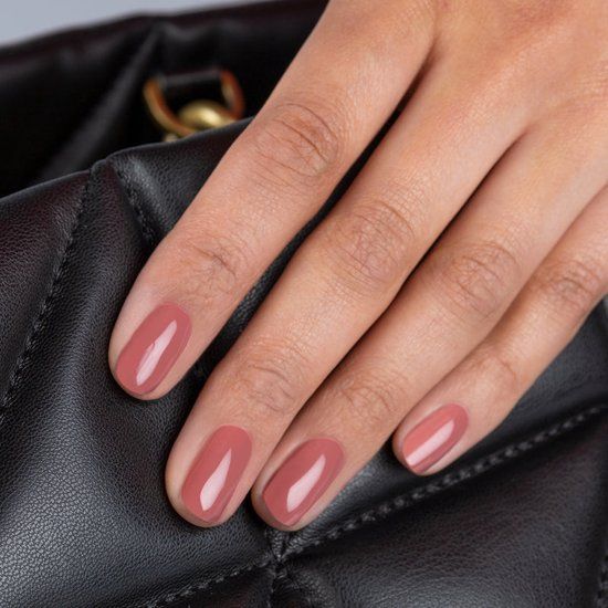 Hand mit lackierten Nägeln in Dusty Rose. Die Hand liegt auf einer schwarzen Tasche.