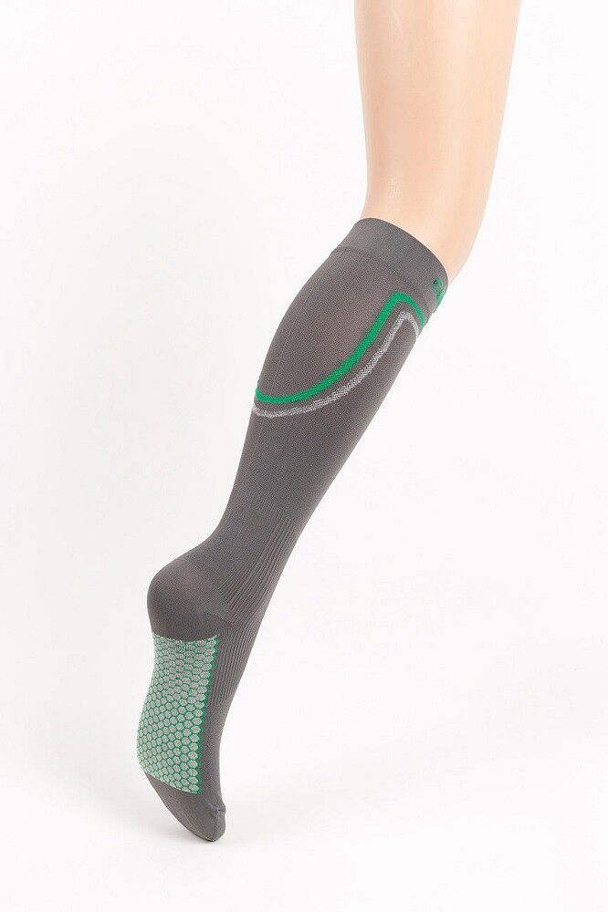 Graue Kniestrümpfe mit grün-grauen Akzenten. Grün-graues Muster an der Sohle. Kompressionsstrümpfe am Bein einer Person.