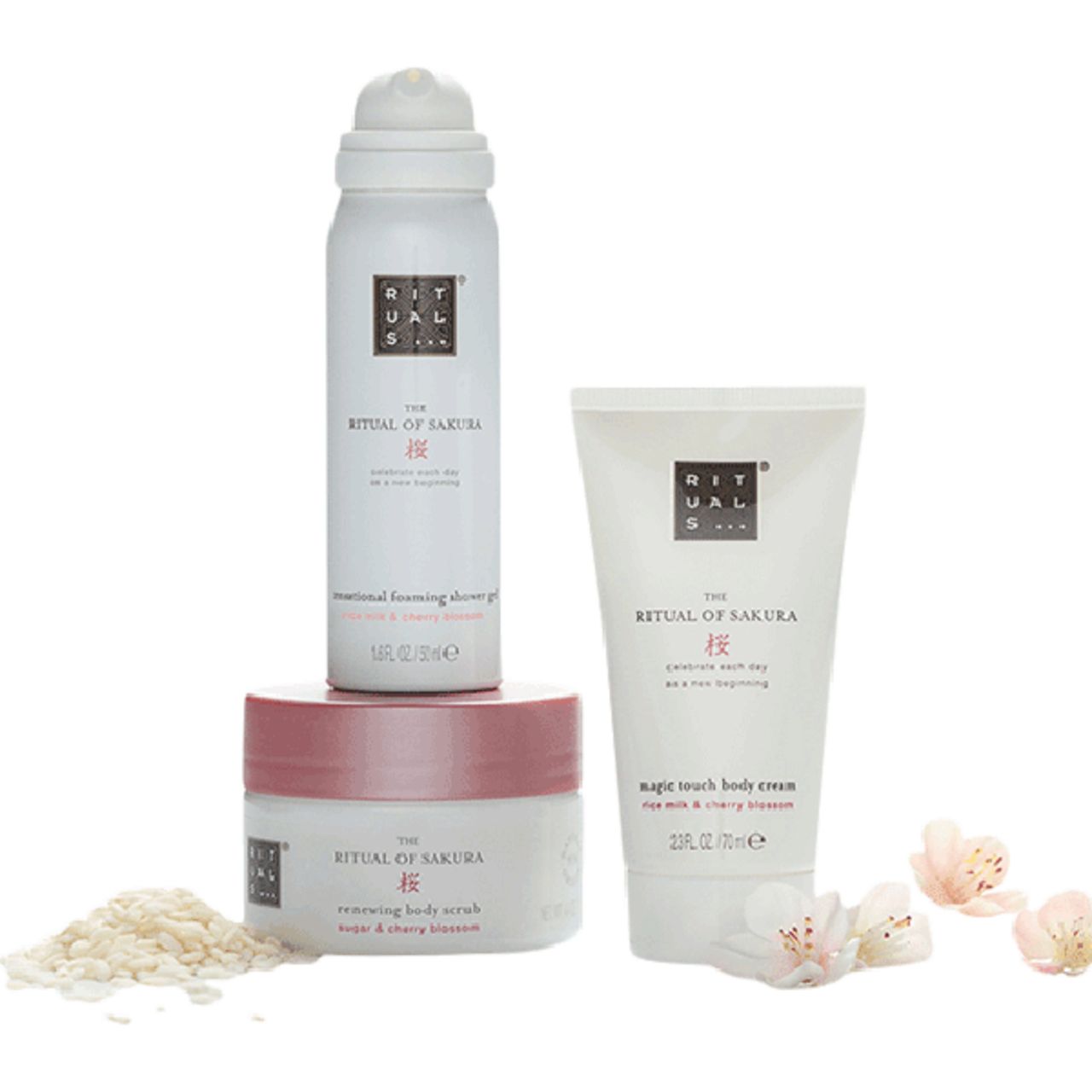 Drei Produkte: Duschschaum, Körpercreme und Körperpeeling. Weiß und rosa Verpackung. Mit Blüten und Körnern dekoriert.