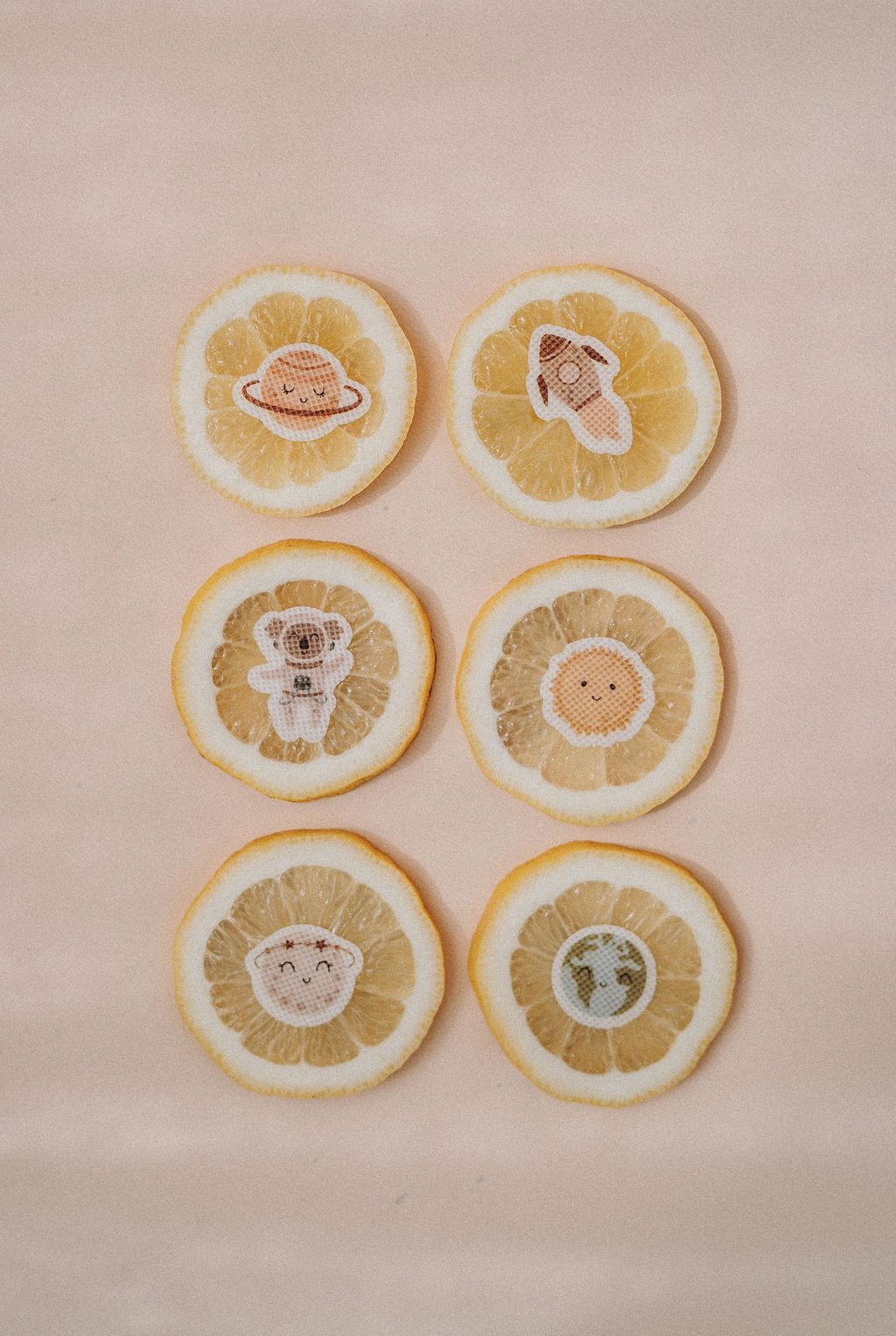 Sechs Zitronenscheiben mit Weltraum-Stickern: Koala, Rakete, Erde, Sonne, Planet, Saturn.