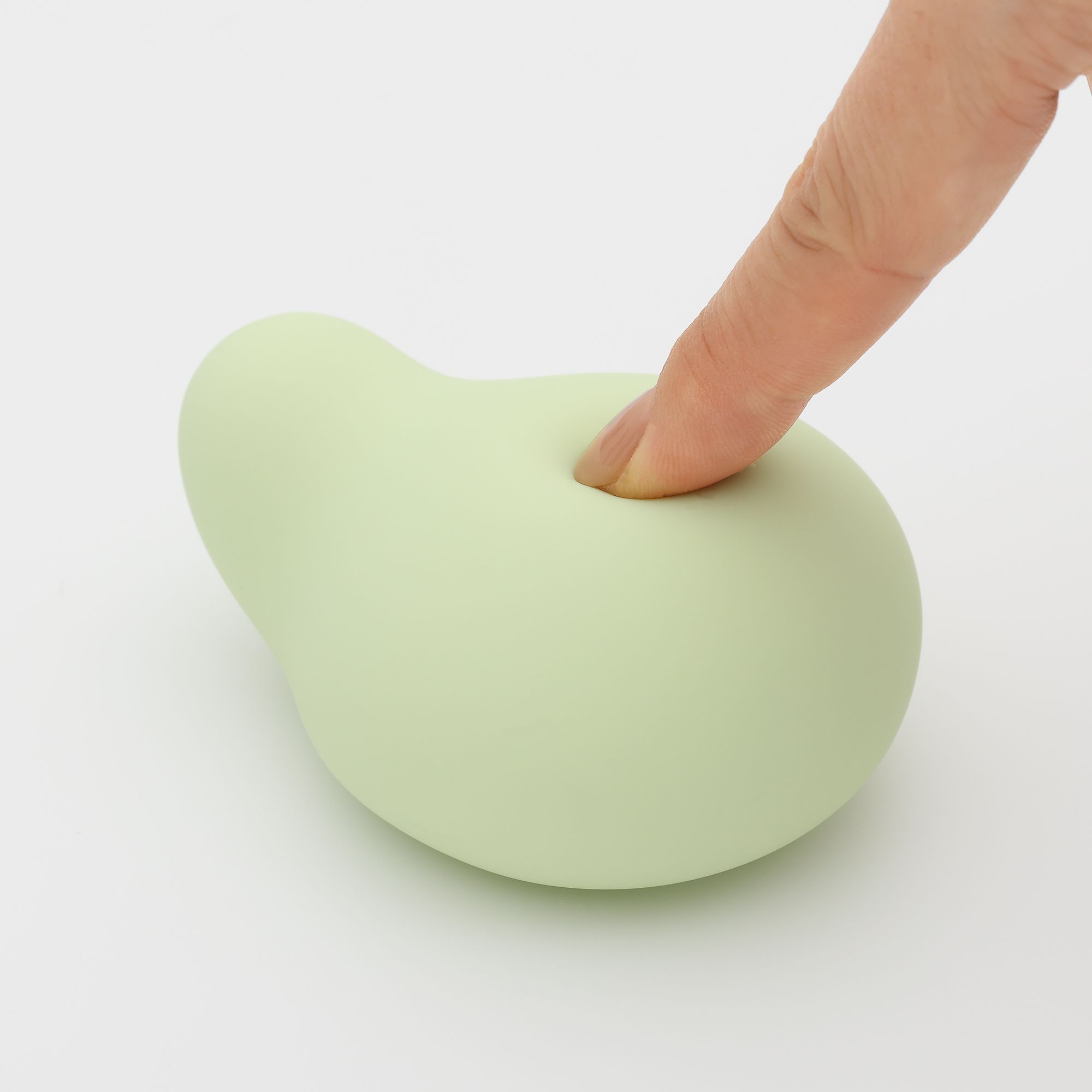 Hellgrüner, birnenförmiger Vibrator. Ein Finger drückt leicht in die Oberfläche.