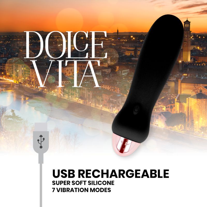 Schwarzer Silikon-Vibrator mit roségoldfarbenem Ende. "Dolce Vita"-Logo und USB-Ladefunktion. Hintergrund: Stadtansicht bei Sonnenuntergang.