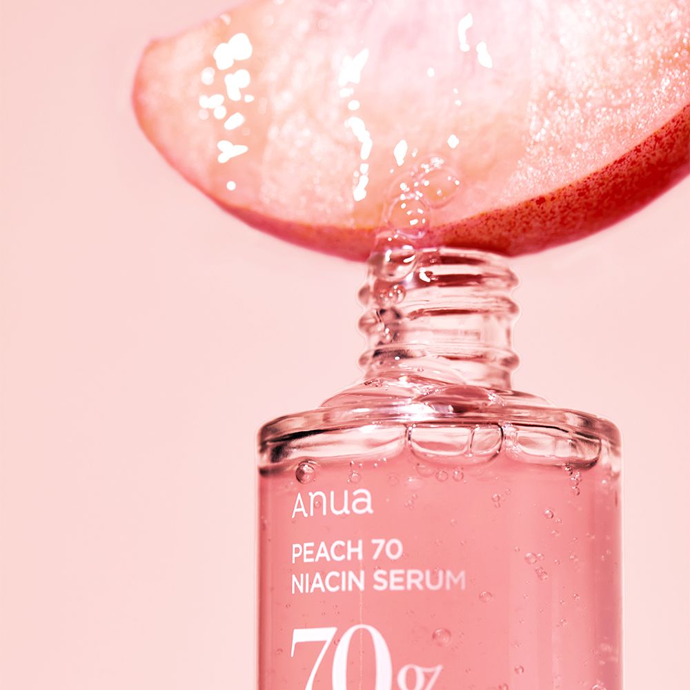 Tropfen aus Pfirsichspalte fallen in Anua Peach 70 Niacin Serumflasche.