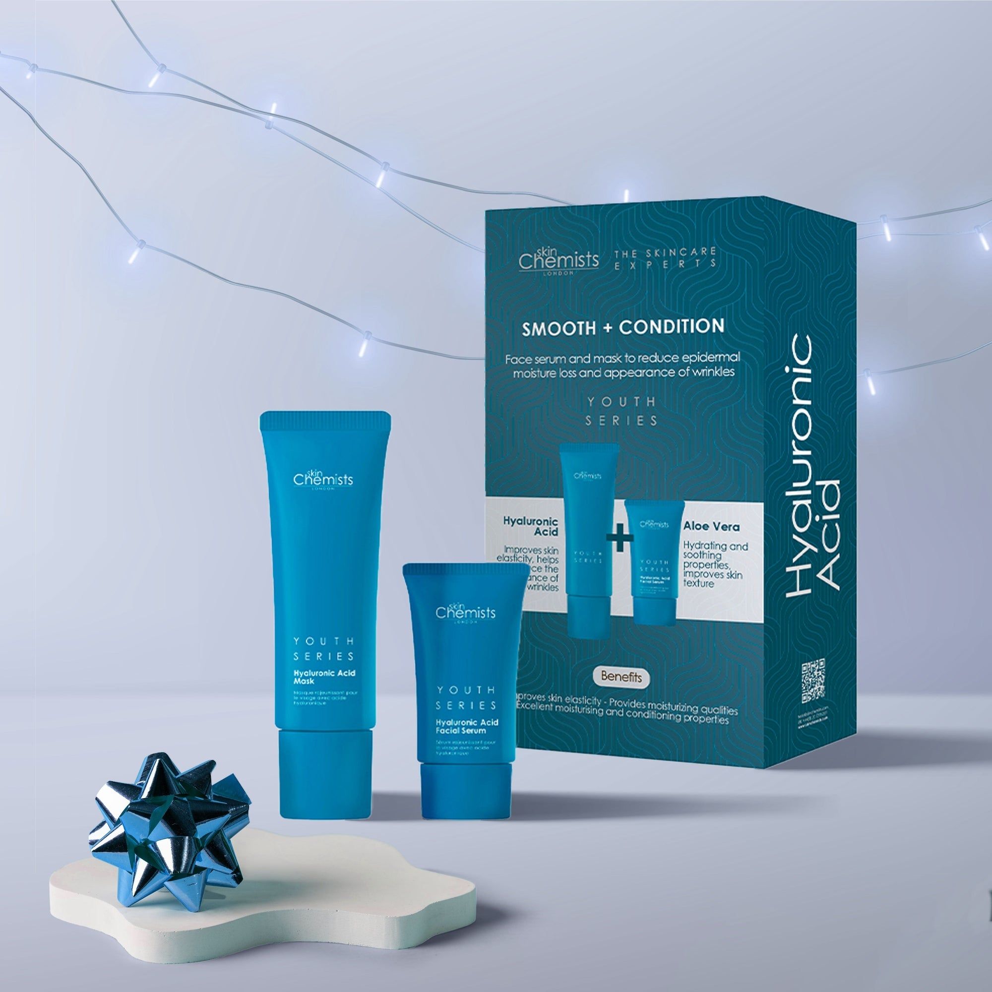 Gesichtsserum und Maske-Set. Blaue Tuben und Verpackung mit Text. "Smooth + Condition" und "Hyaluronic Acid" sind sichtbar. Dekoration.