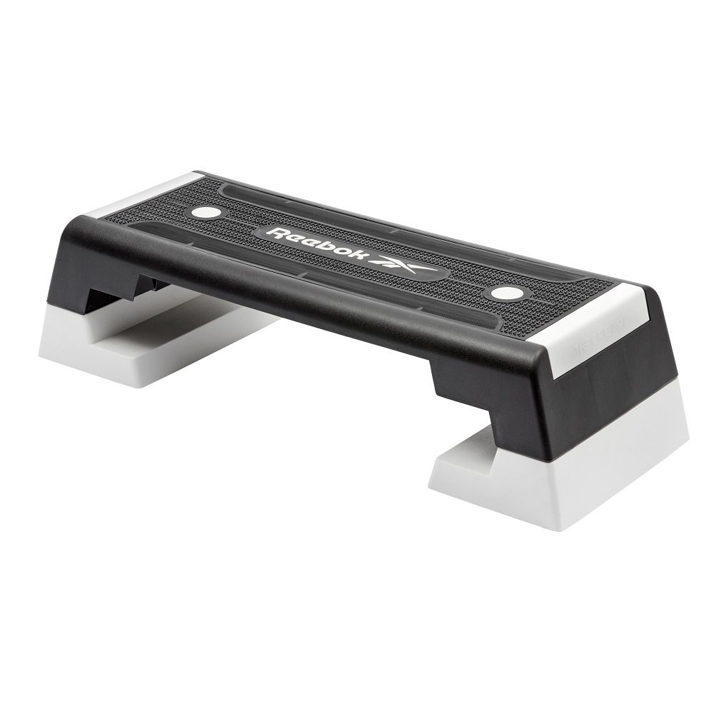 Schwarzer Reebok Step mit weißen Füßen. Schwarze Oberfläche mit Rillen. Reebok Logo.