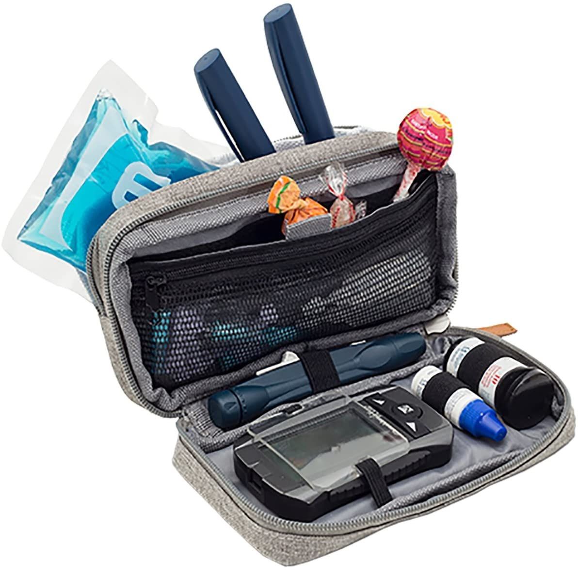 Geöffnete graue Tasche mit Insulinpens, Teststreifen, Blutzuckermessgerät, Kühlpack und Süßigkeiten.