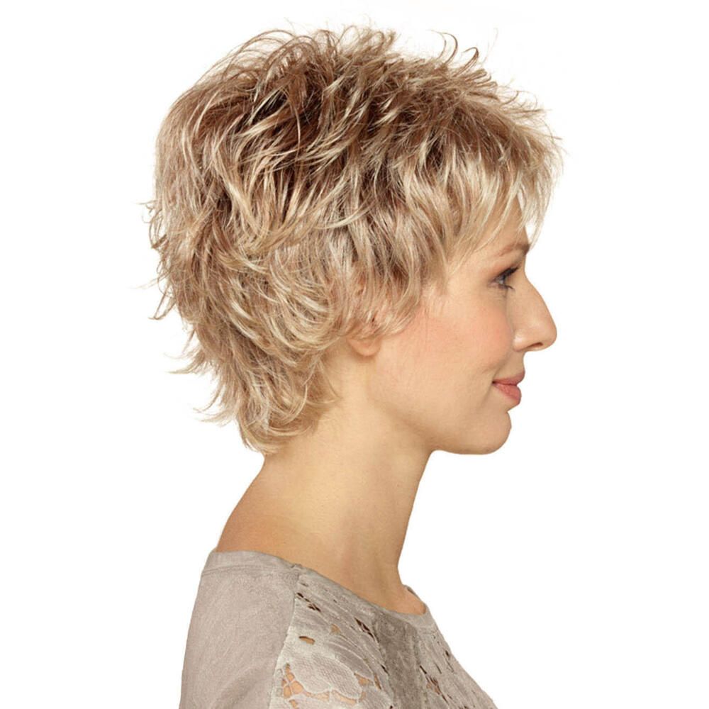 Kurzhaarperücke in Blondtönen. Seitenansicht. Die Frau trägt ein graues Oberteil.
