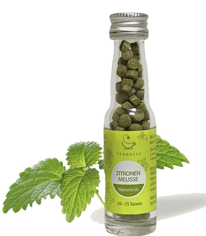 Glasflasche mit grünen Teeballs. Etikett mit Text und Logo. Zitronenmelisse-Blätter liegen daneben.