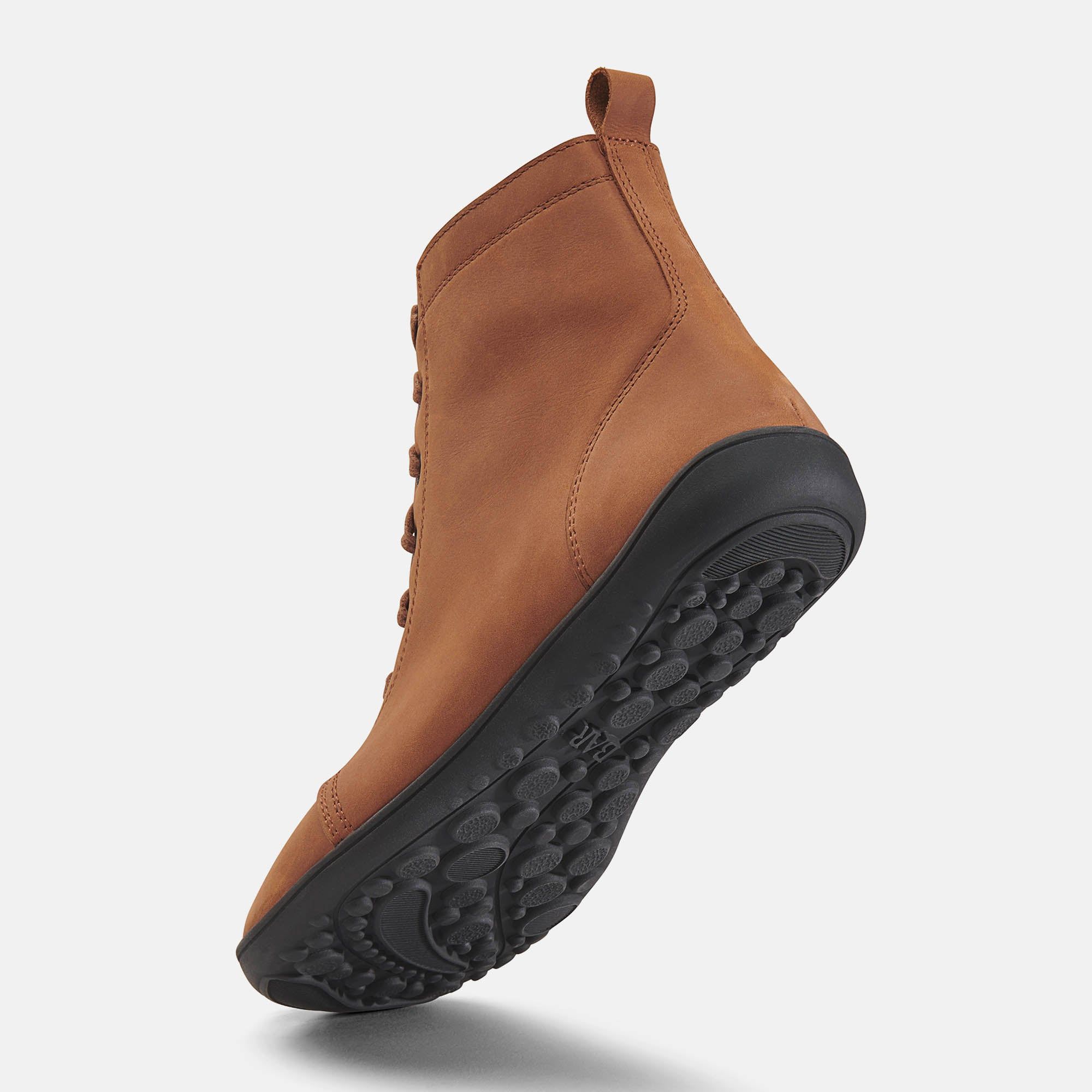 Braune Stiefelette von unten. Schwarze Sohle, Profil. Ferse und Knöchel sichtbar.