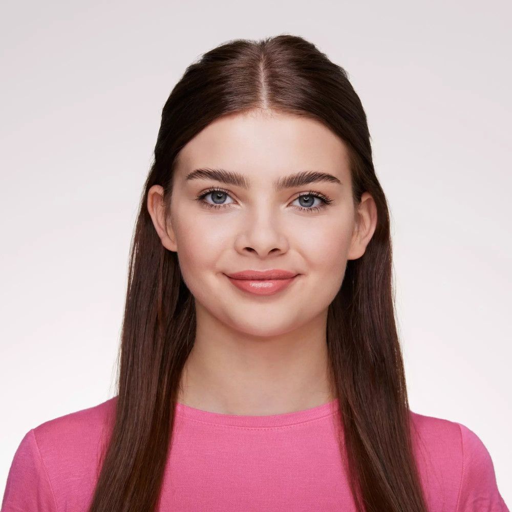 Porträt einer jungen Frau mit braunen Haaren und einem rosa Oberteil. Sie lächelt.