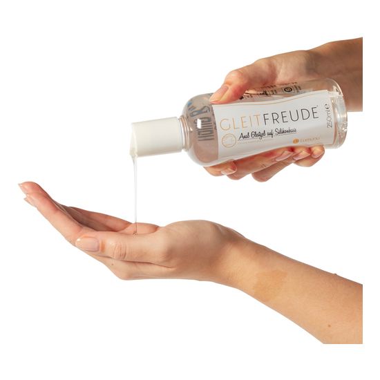 Eine Hand hält eine Flasche, aus der eine klare Flüssigkeit in die andere Hand gegossen wird. Aufschrift: Gleitfreude.