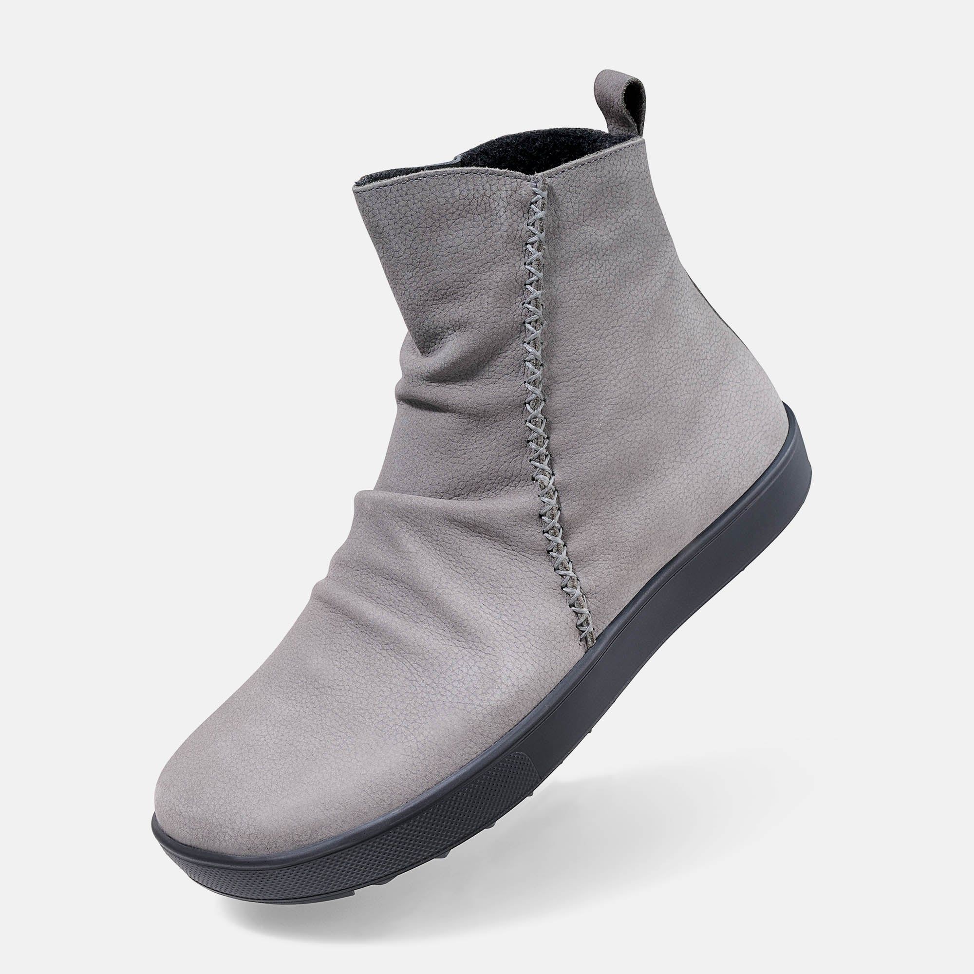 Graue Stiefelette mit schwarzer Sohle. Ziernähte am Schaft. Faltenwurf. Blick von der Seite.