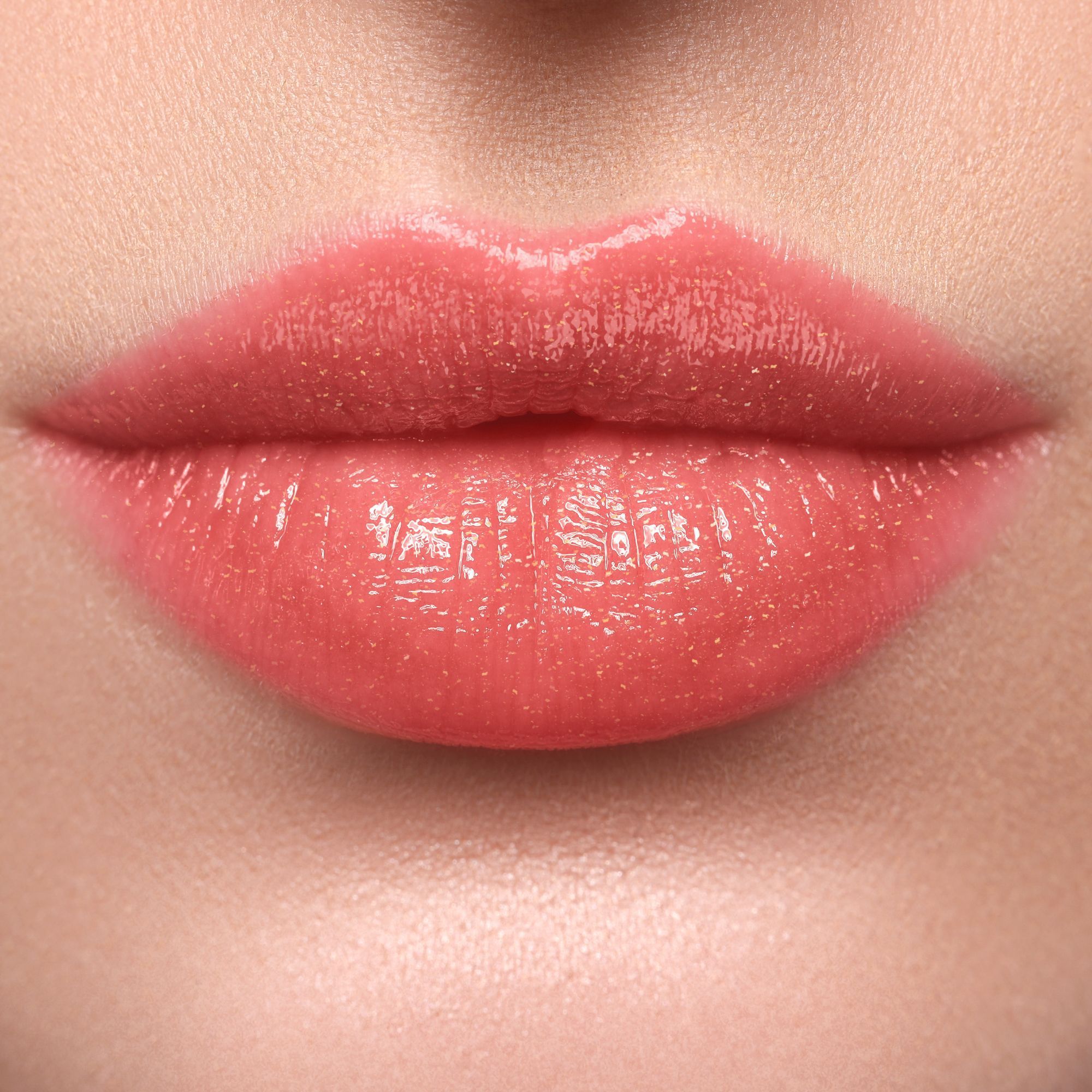 Nahaufnahme von Lippen, die mit einem glänzenden, rosafarbenen Lippenstift bemalt sind. Die Lippen sind leicht geöffnet.