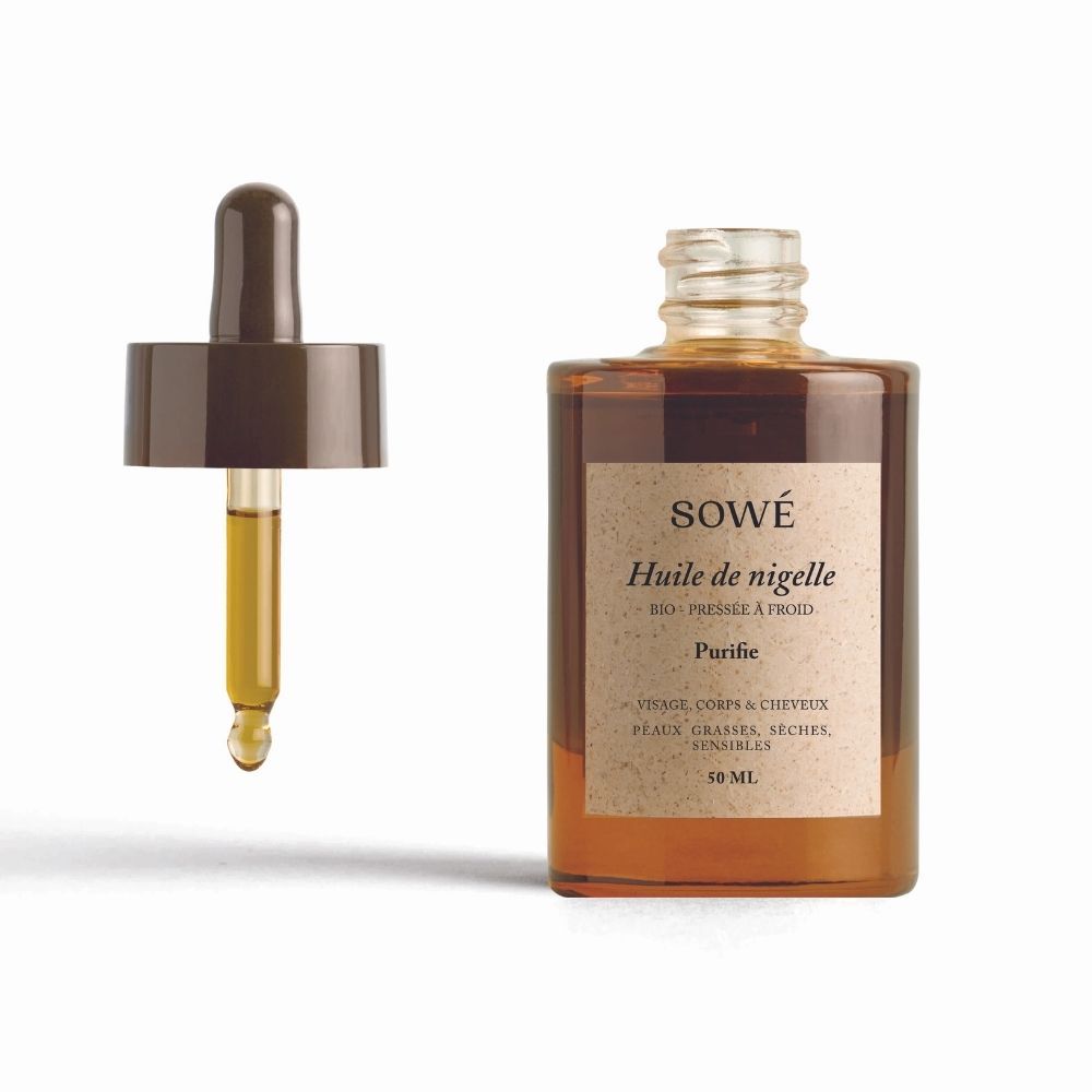 Braune Glasflasche mit Pipette. Etikett mit "SOWÉ Huile de nigelle". Pipette mit Öl daneben.