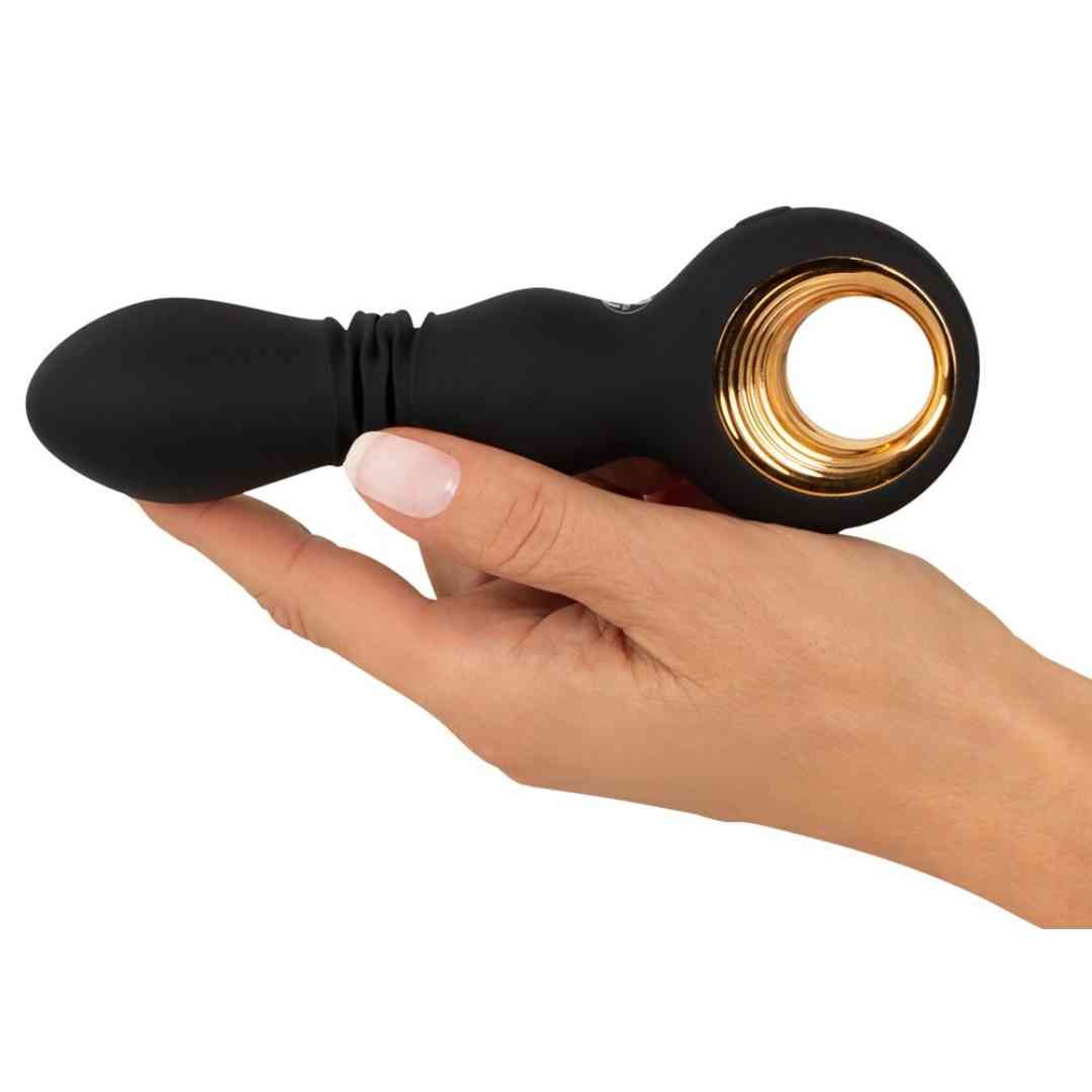 Schwarzer Vibrator in Hand gehalten. Goldener Ring, geriffelte Mitte, ovale Form.