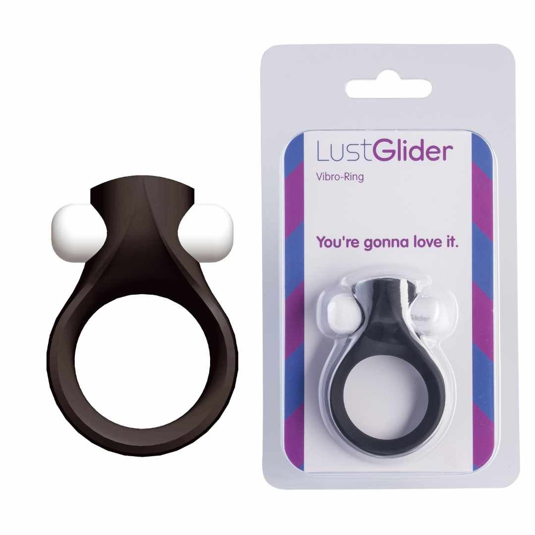 Schwarzer Ring mit zwei weißen Erhebungen, neben Verpackung. Verpackung mit Produktname und Text.