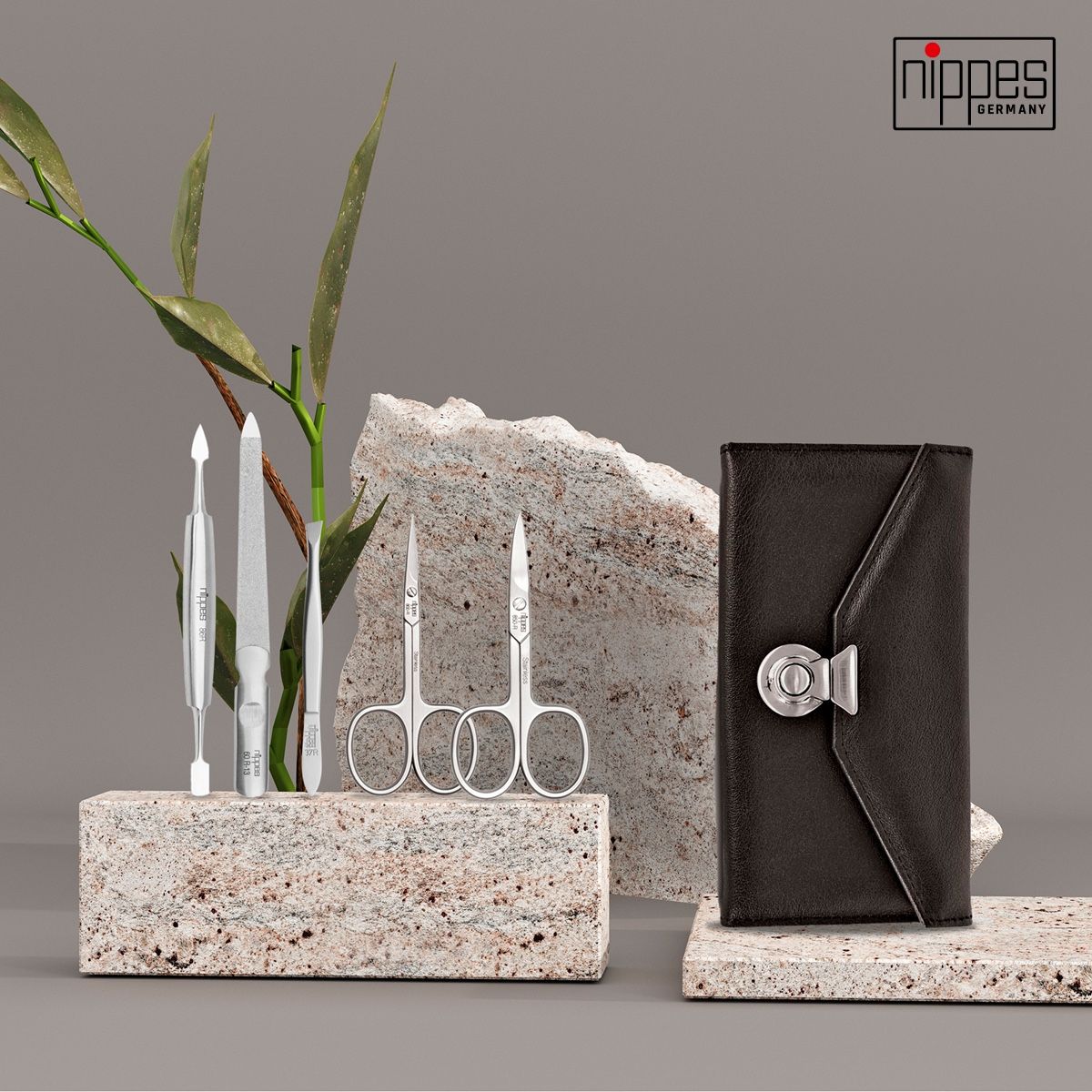 Maniküre-Etui mit Werkzeugen auf Stein. Enthält Schere, Feile und weitere Werkzeuge. Schwarzes Lederetui mit silbernem Verschluss.