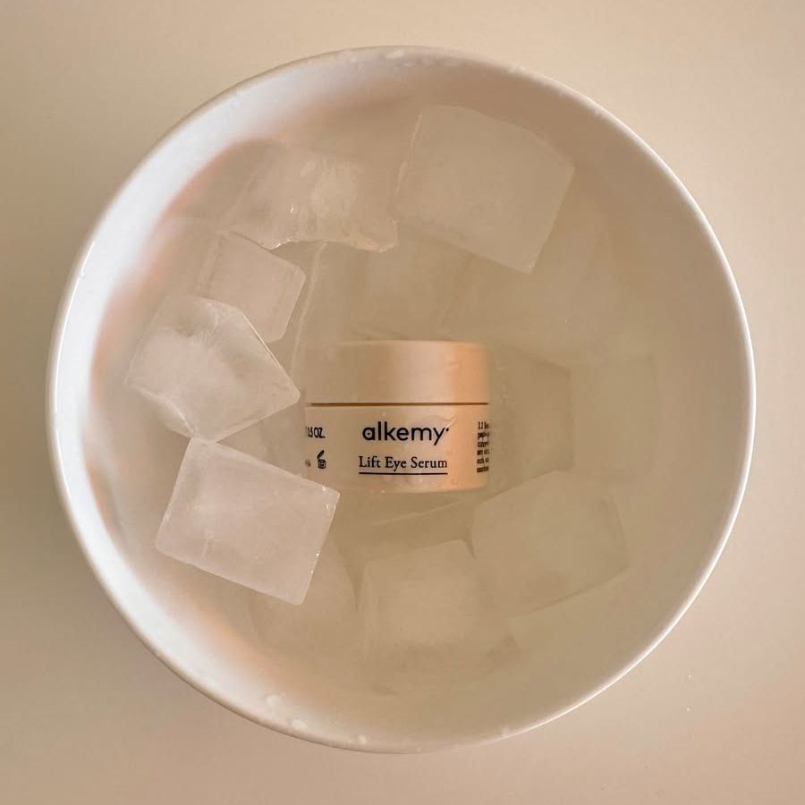 Alkemy Lift Eye Serum Tiegel in einer Schüssel mit Eiswürfeln.