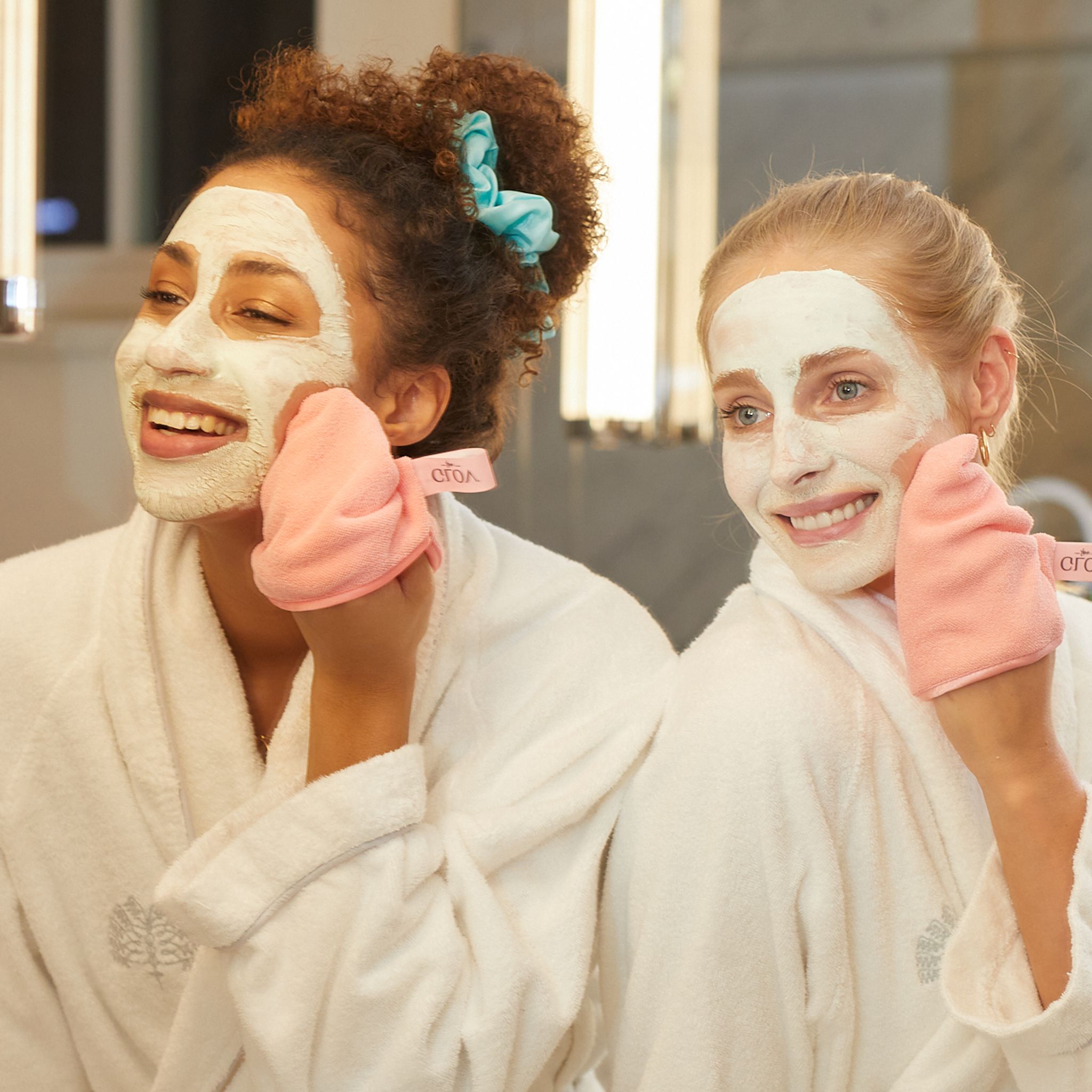 Zwei Frauen mit Gesichtsmasken und rosa Wattepads.