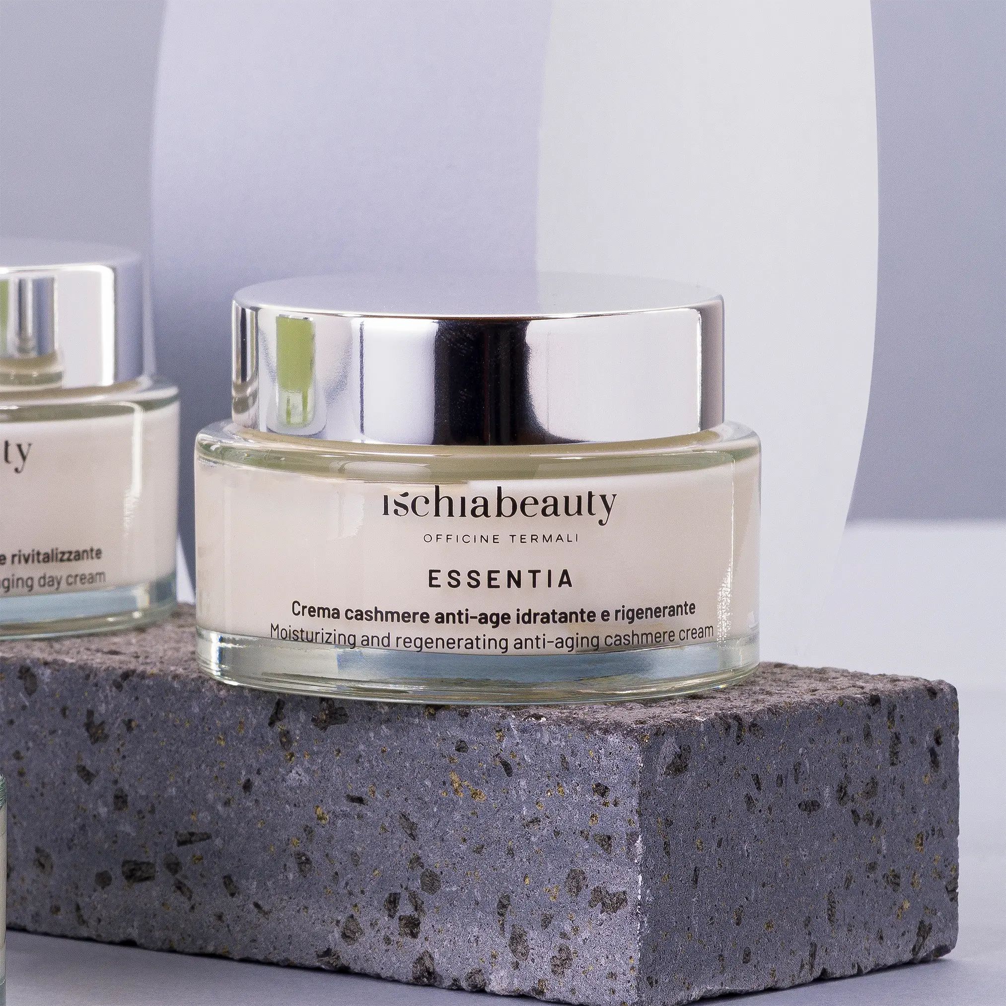 Creme-Dose mit silbernem Deckel. Text: ischiabeauty, ESSENTIA. Auf Steinblock platziert.
