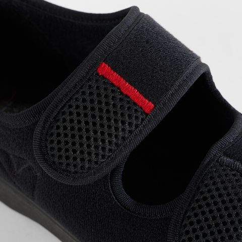 Schwarze Komfortschuhe mit Klettverschluss und roter Zierleiste.