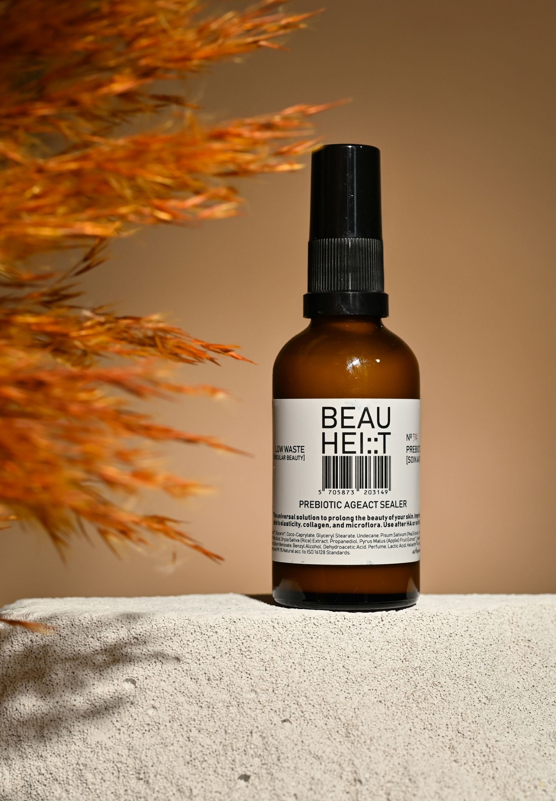 Braune Glasflasche mit schwarzem Sprühkopf. Weißes Etikett mit Text: BEAUHEIT Prebiotic AgeAct Sealer. Produktname und Inhaltsstoffe.