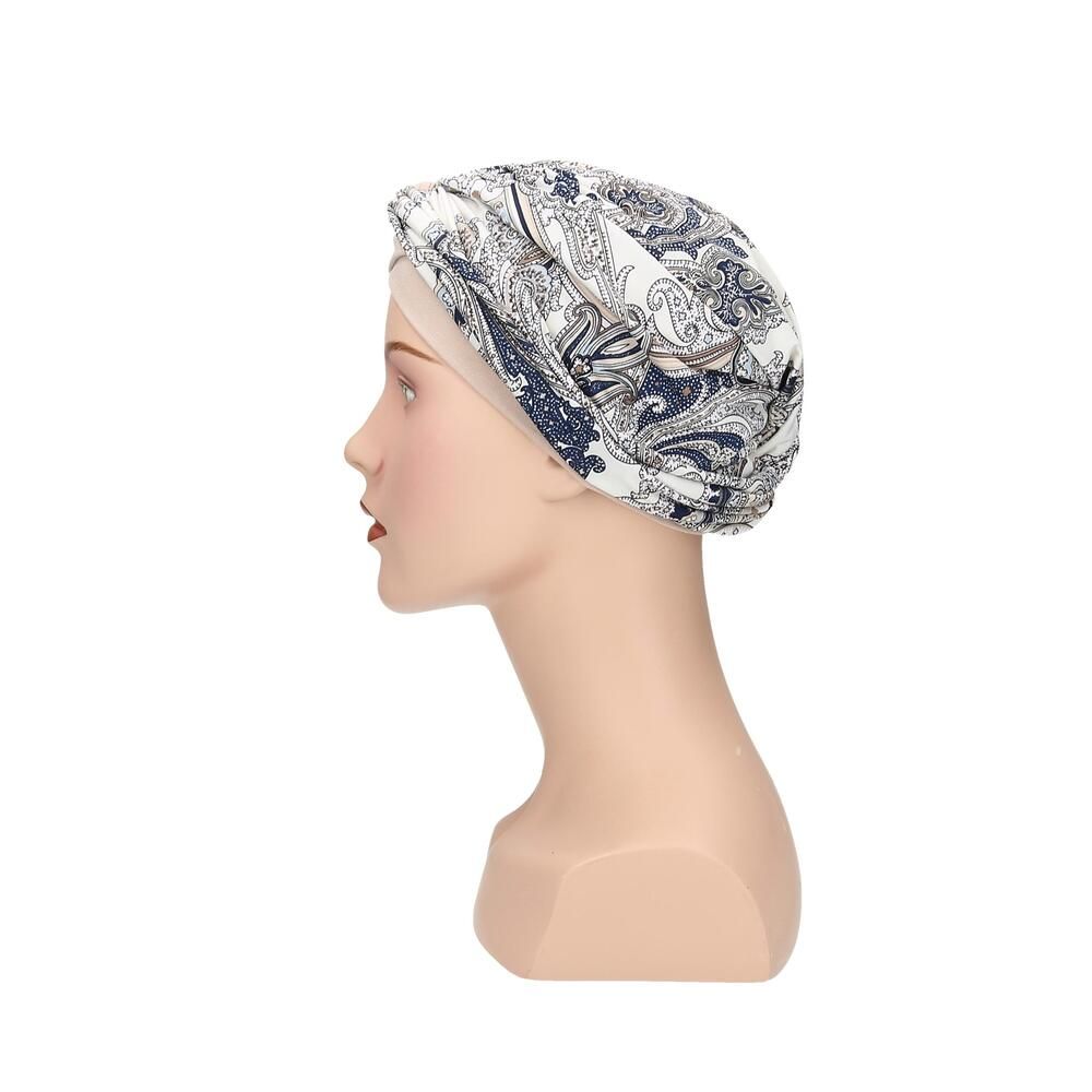 Turban Livia von Turbane. Beige Untertuch, bedruckter Stoff in Weiß, Blau und Grau. Auf einer Büste.