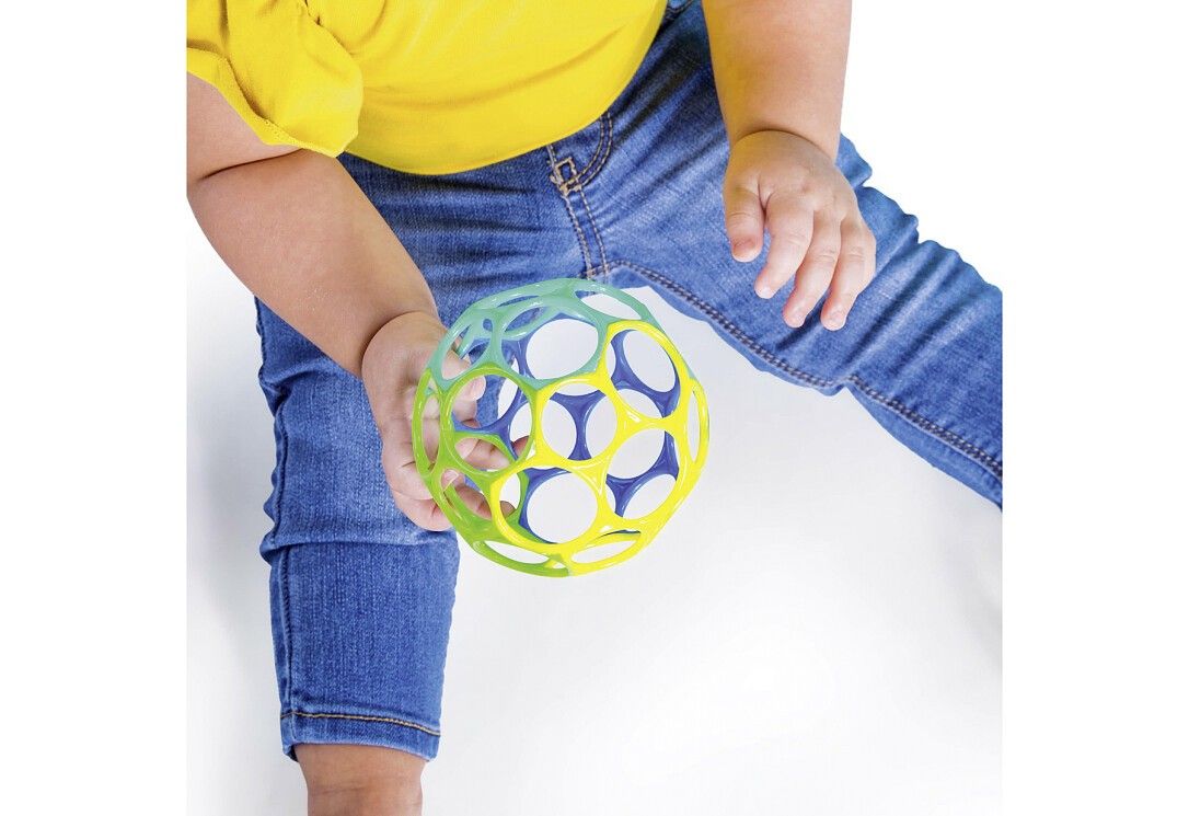 Ein Kind hält einen bunten, offenen Ball. Der Ball hat runde Öffnungen und ist aus Kunststoff.