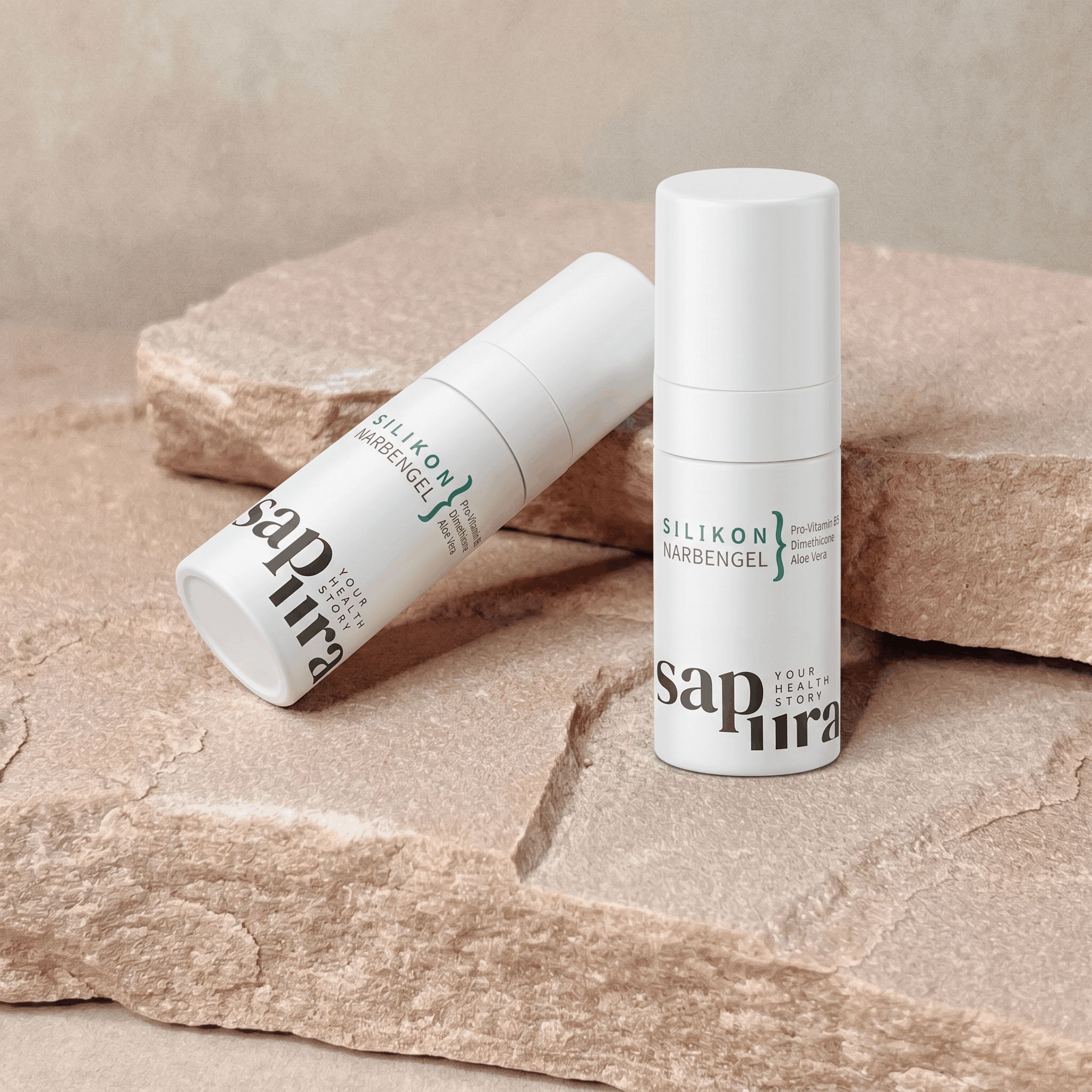 Zwei Flaschen Silikon Narbengel, Pro-Vitamin B5 und Aloe Vera, auf Steinen.