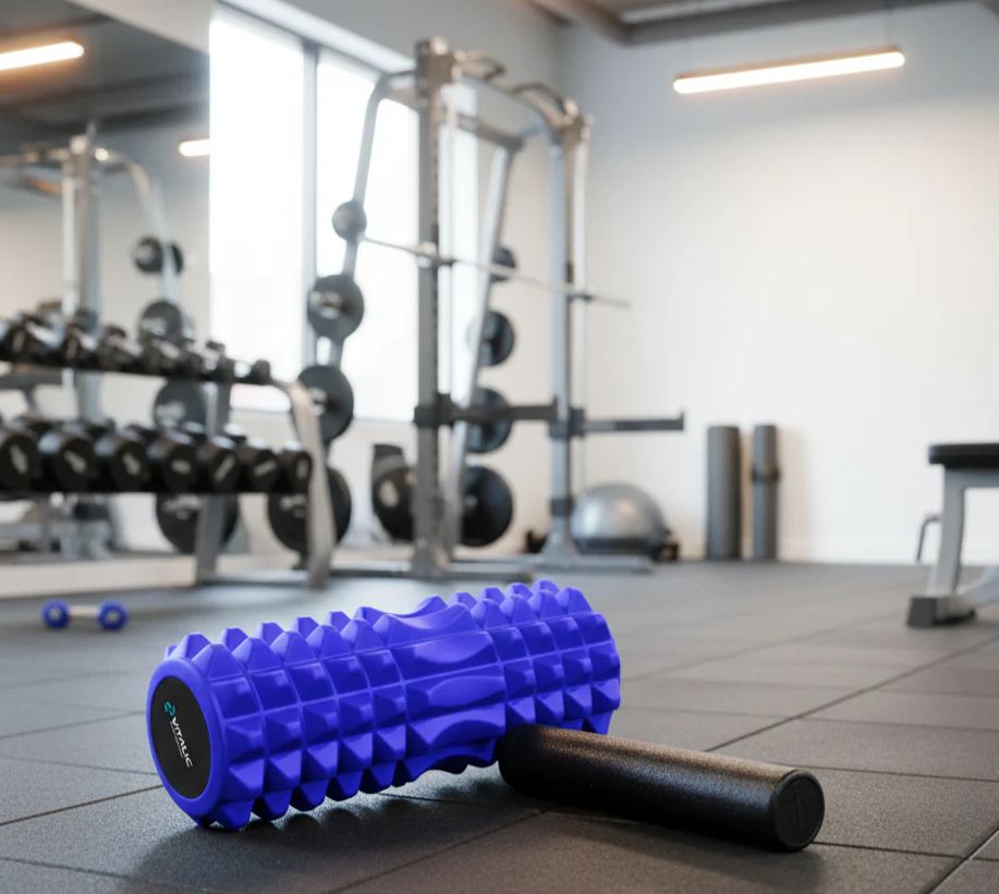 Blau Triggerpunkt-Massagerolle und schwarze Mini-Rolle auf dem Boden in einem Fitnessstudio. VITALIC-Logo auf der Rolle.