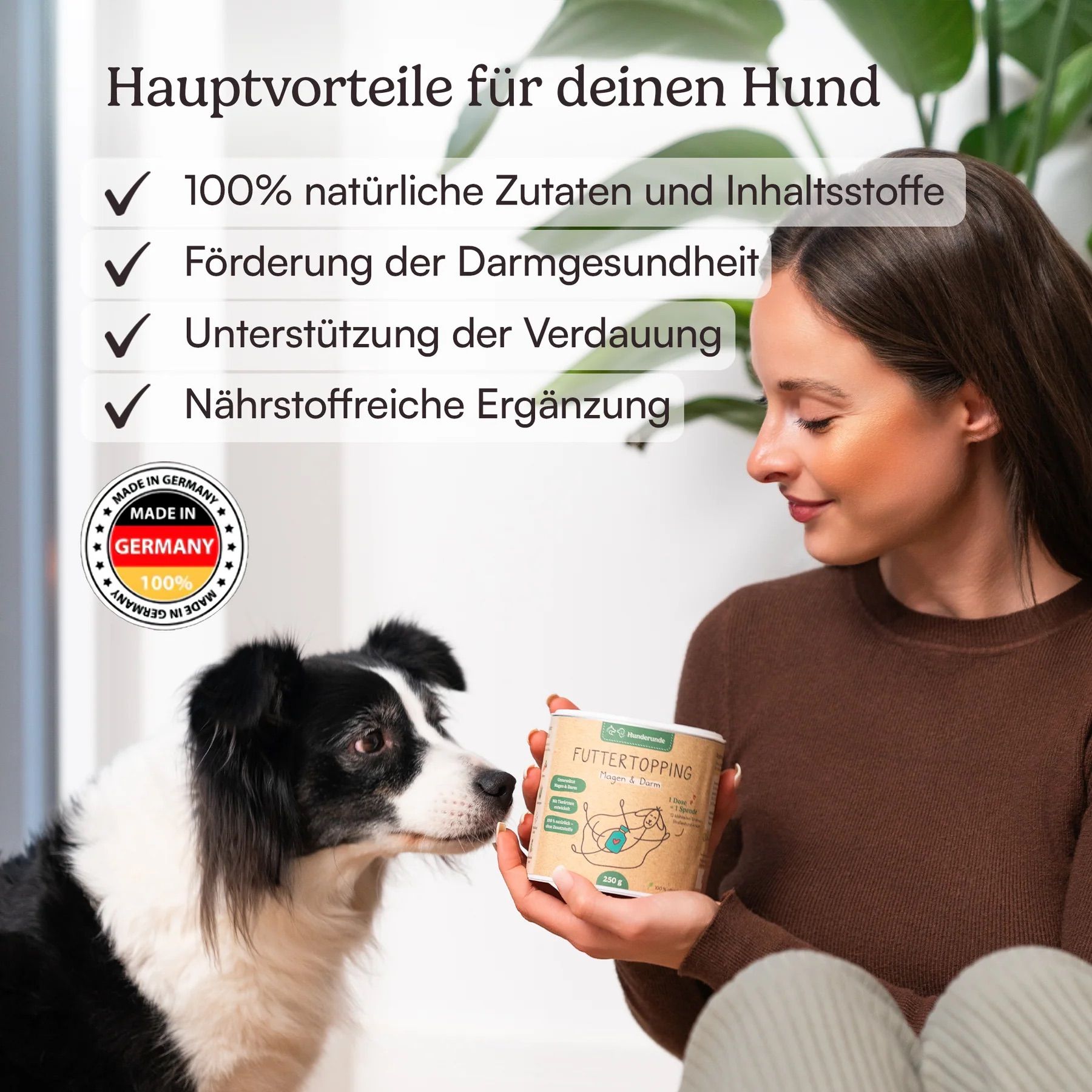 Frau hält Dose Futtertopping. Hund schaut auf Dose. Auf der Dose: Futtertopping Magen & Darm. Made in Germany-Siegel.
