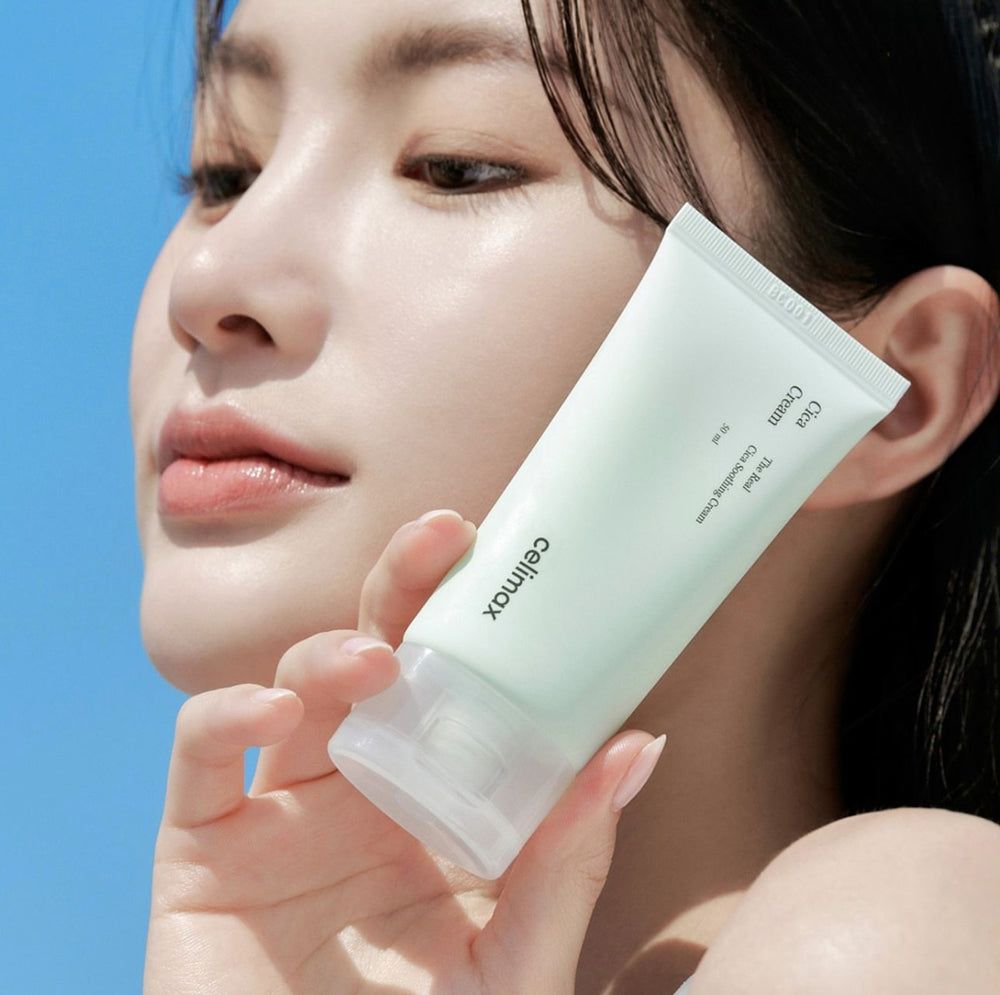 Frau hält Celimax Cica Creme Tube vor blauem Himmel.