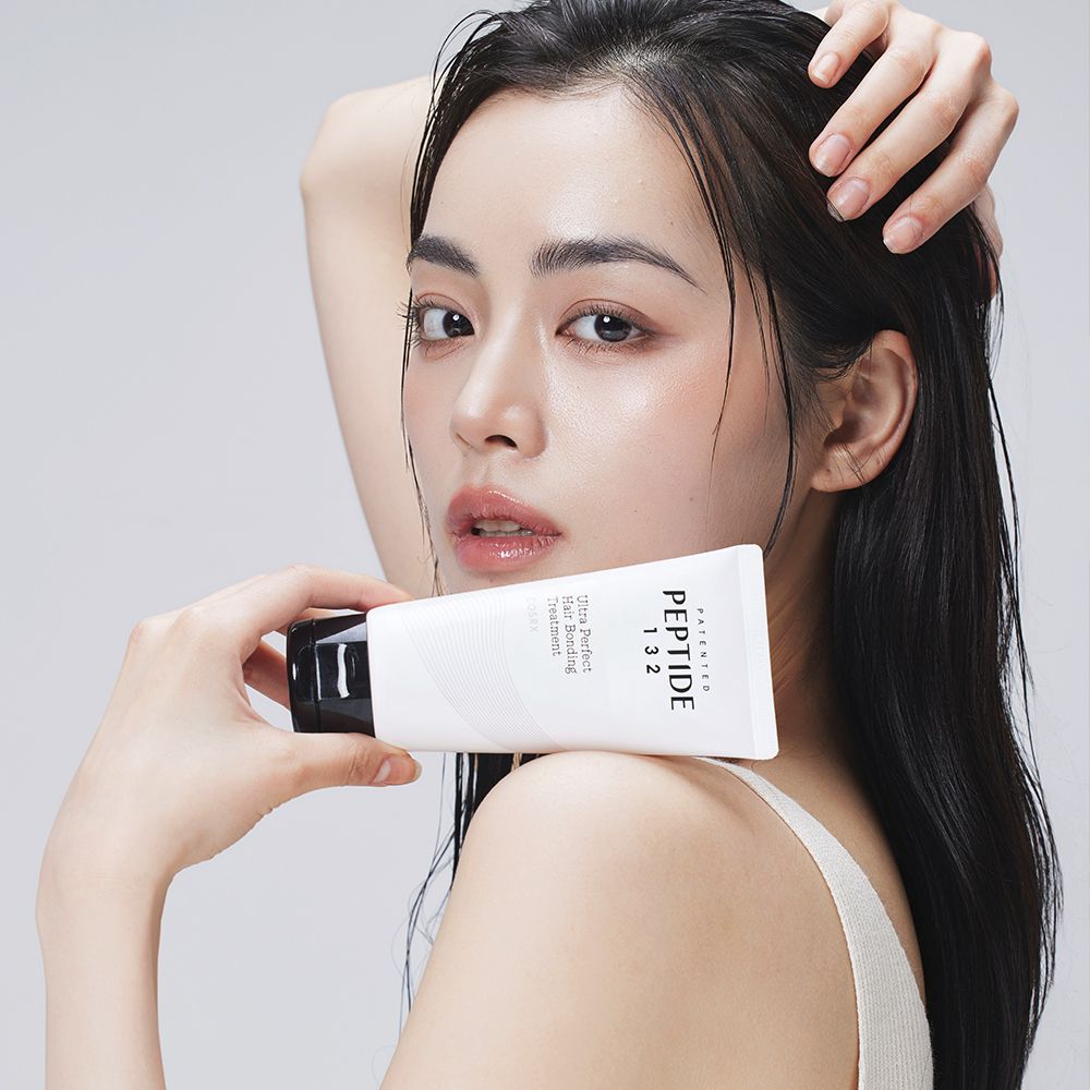 Frau hält eine weiße Tube mit der Aufschrift PEPTIDE 132 Ultra Perfect Hair Bonding Treatment.