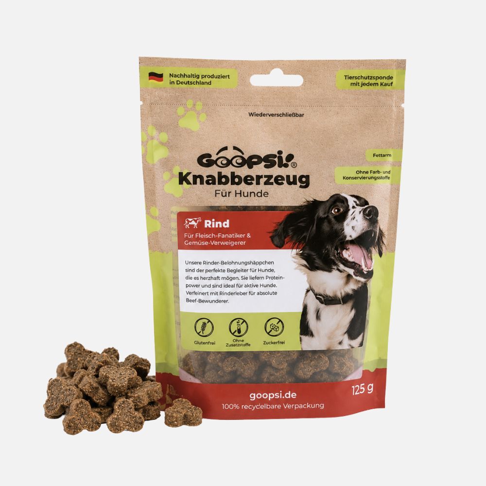 Eine Tüte Goopsi Hundeleckerlis mit einem Haufen Leckerlis davor. Die Tüte zeigt einen Hund und Produktinfos.