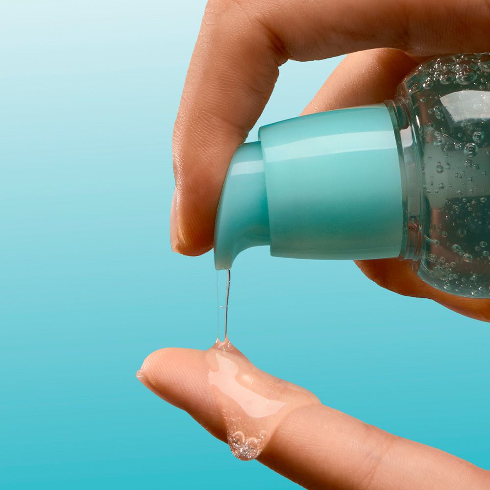Eine Hand drückt eine Pumpe, um eine klare Flüssigkeit auf einen Finger zu geben.