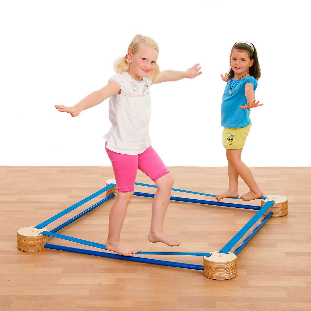 Zwei Mädchen balancieren auf einem quadratischen Slackspot mit blauen Gurten und Holzsockeln.
