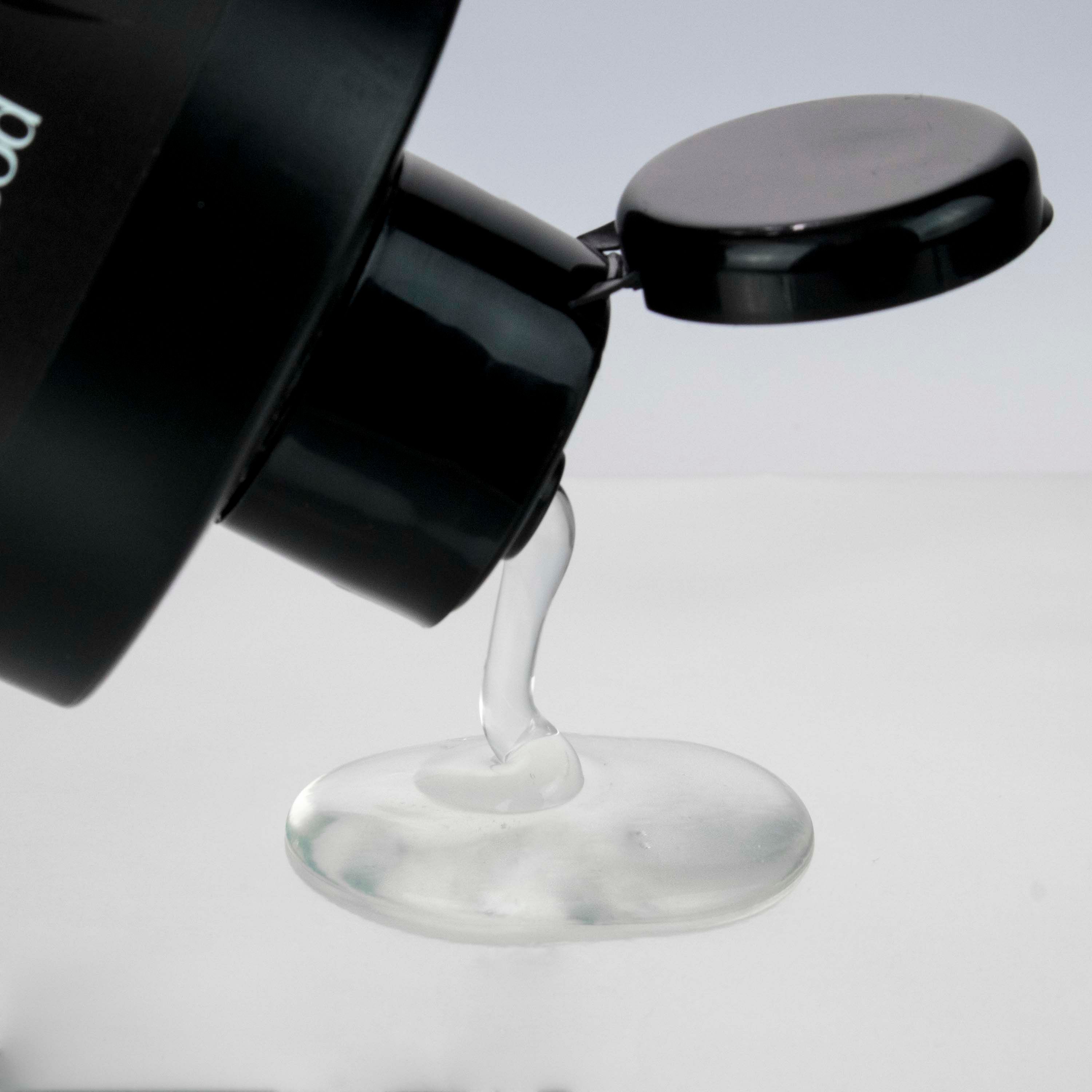 Klares Shampoo, das aus einer schwarzen Flasche gegossen wird.