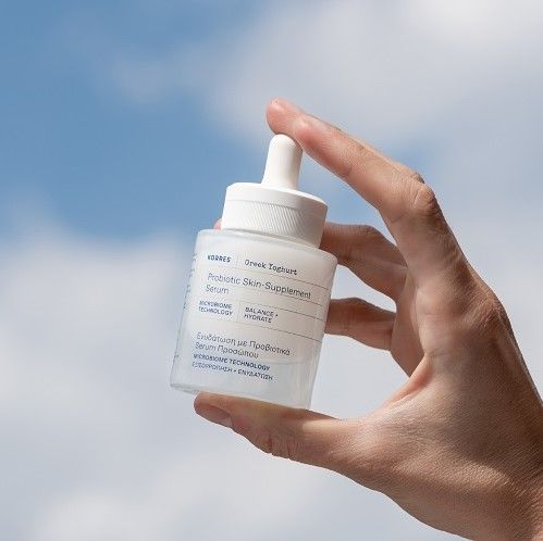 Hand hält Serumflasche. Weiße Flasche mit Pipette. Aufschrift 'KORRES' und 'Probiotic Skin-Supplement'.