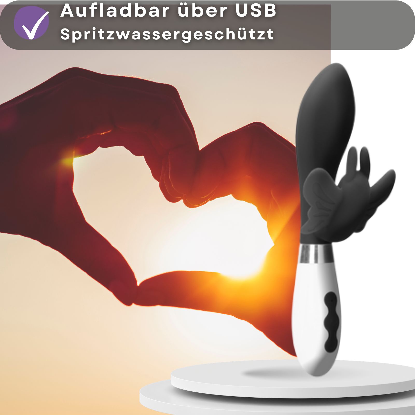 Vibrator, aufladbar über USB, spritzwassergeschützt. Schwarzer Kopf, weißer Griff. Herz-Geste im Hintergrund.