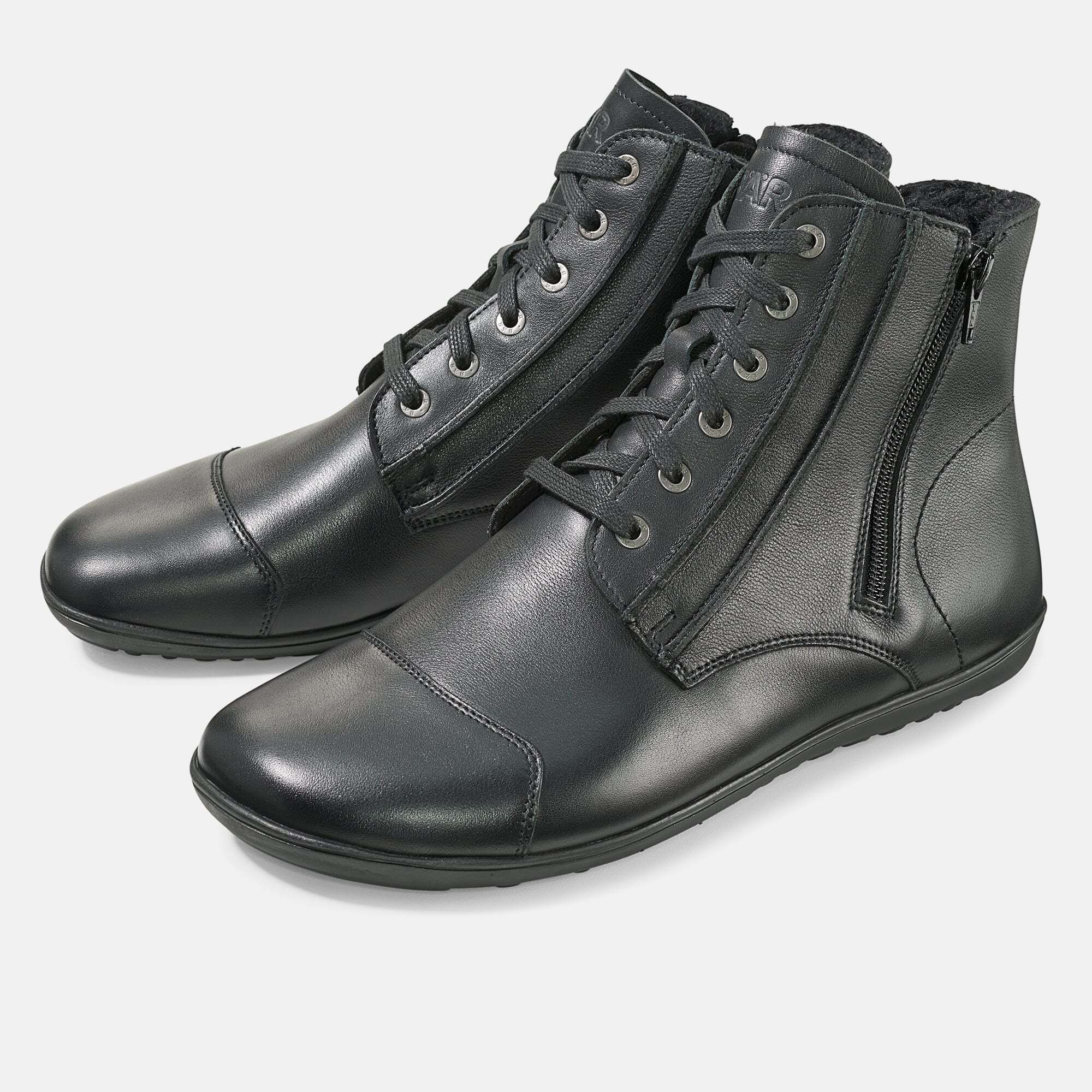 Schwarze Stiefelette mit Schnürung und Reißverschluss. Lederoptik, flache Sohle. Schuh von der Seite, leicht schräg.
