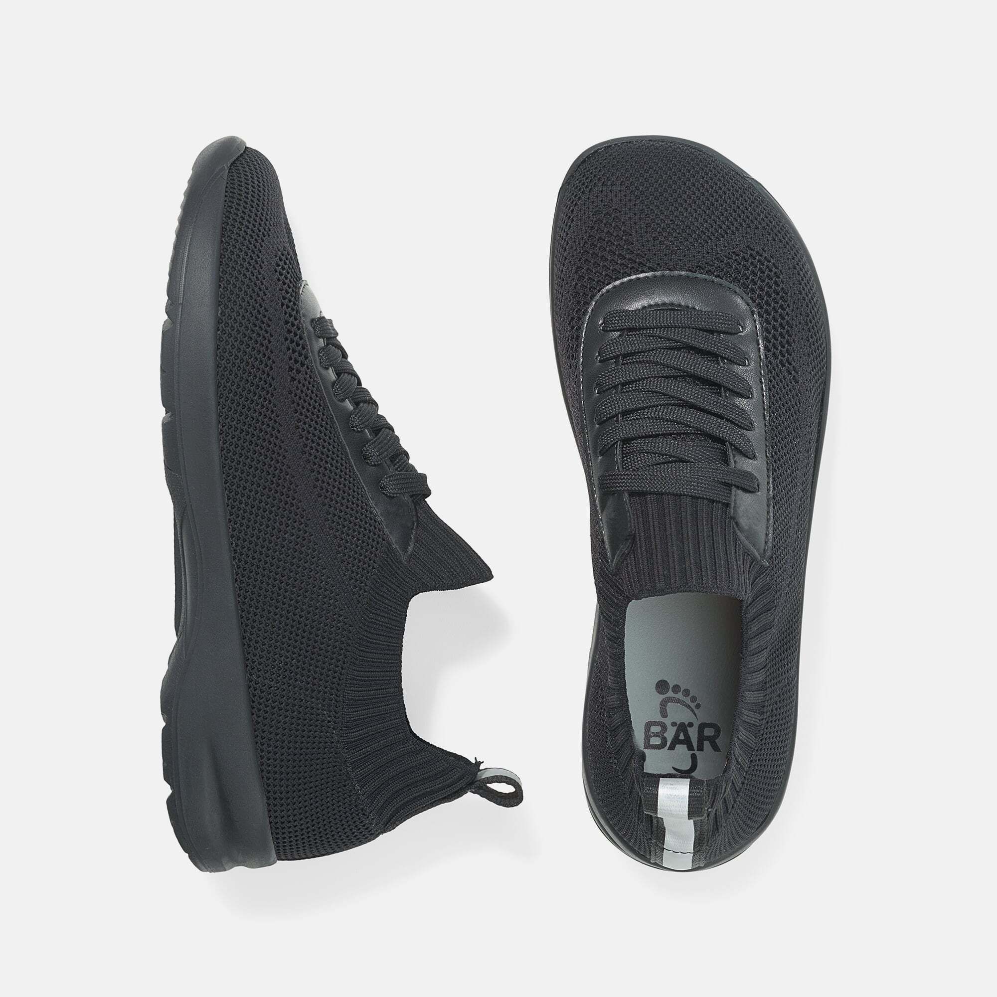 Zwei schwarze Herren-Schnürschuhe. Mesh-Obermaterial, Schnürsenkel, breite Passform. Sohle mit BAR-Logo. Details: Leder-Applikationen.