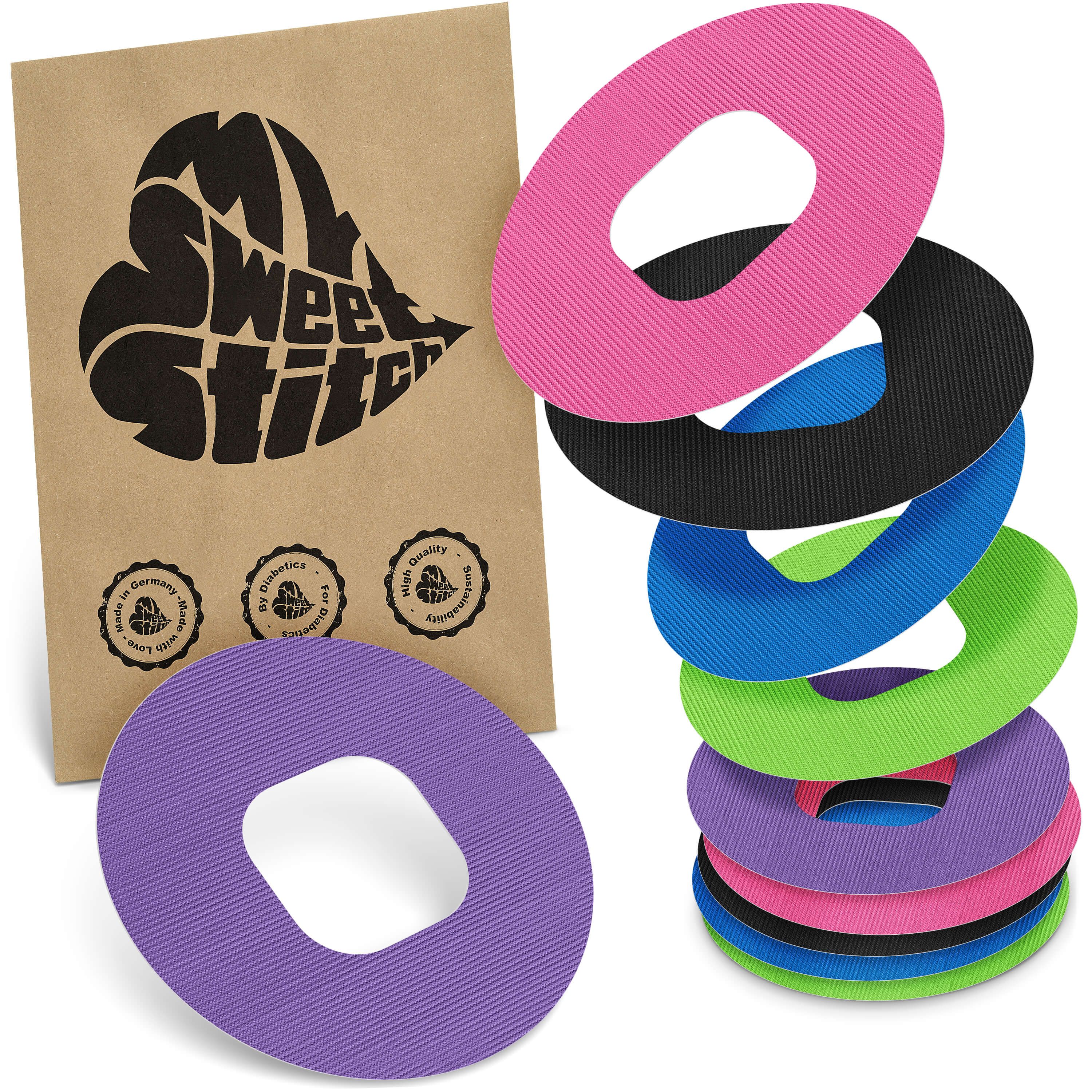 Verschiedenfarbige, ringförmige Pflaster mit ovaler Aussparung. Braune Verpackung mit Logo und Qualitätssiegeln.