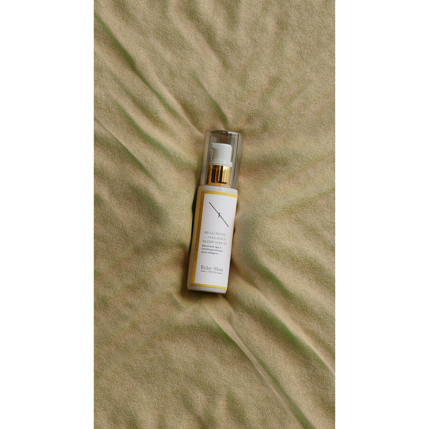 Serumflasche mit goldenem Deckel. Beschriftung: Hyaluronsäure + Collagen Elixir Serum. Hintergrund: gelbes Tuch.