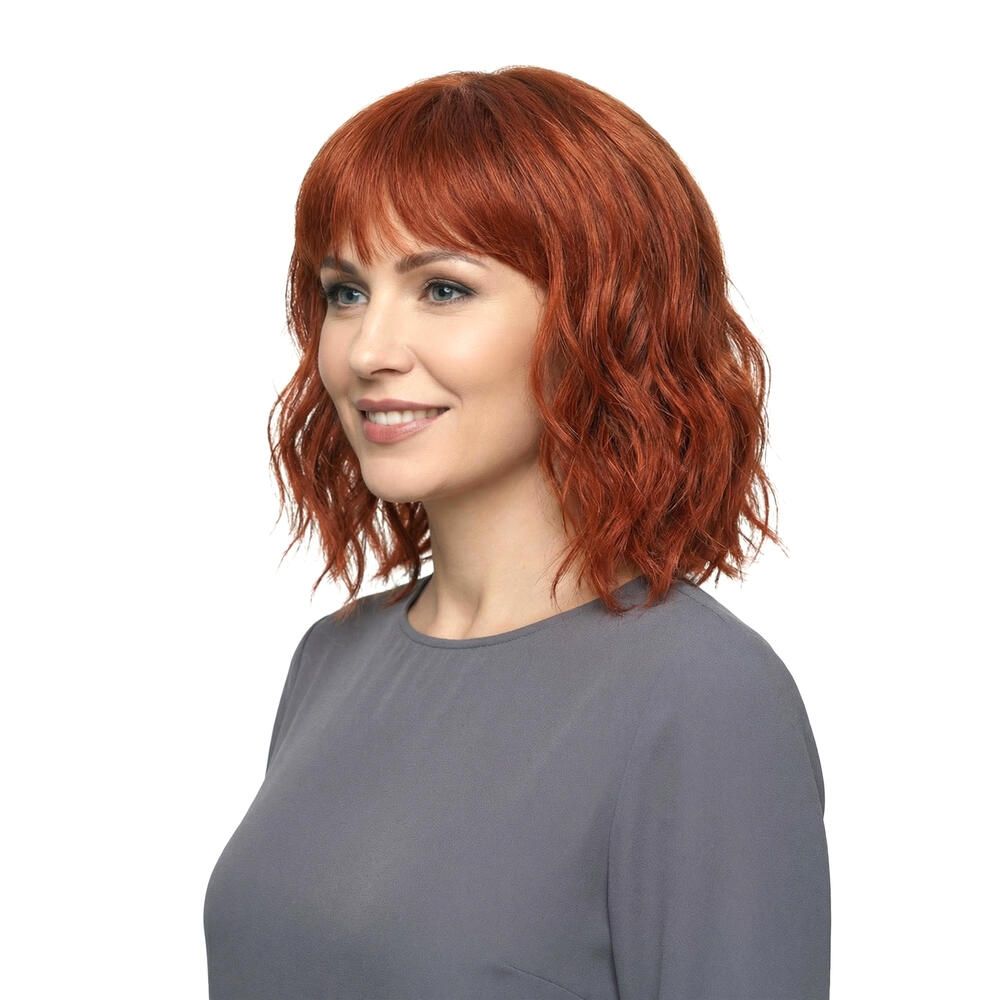 Rote Perücke mit Pony. Die Frau trägt ein graues Oberteil. Seitenansicht.