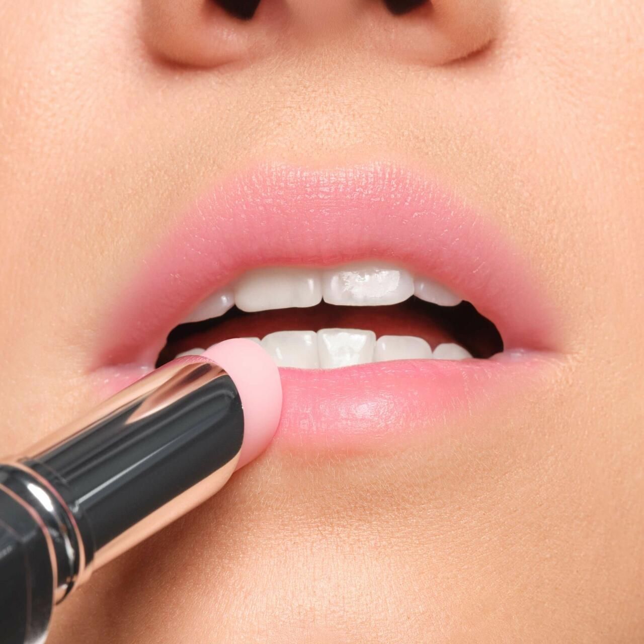 Nahaufnahme von Lippen, die mit einem Lippenbalsam bestrichen werden. Der Lippenbalsam ist in einer silbernen Hülse.