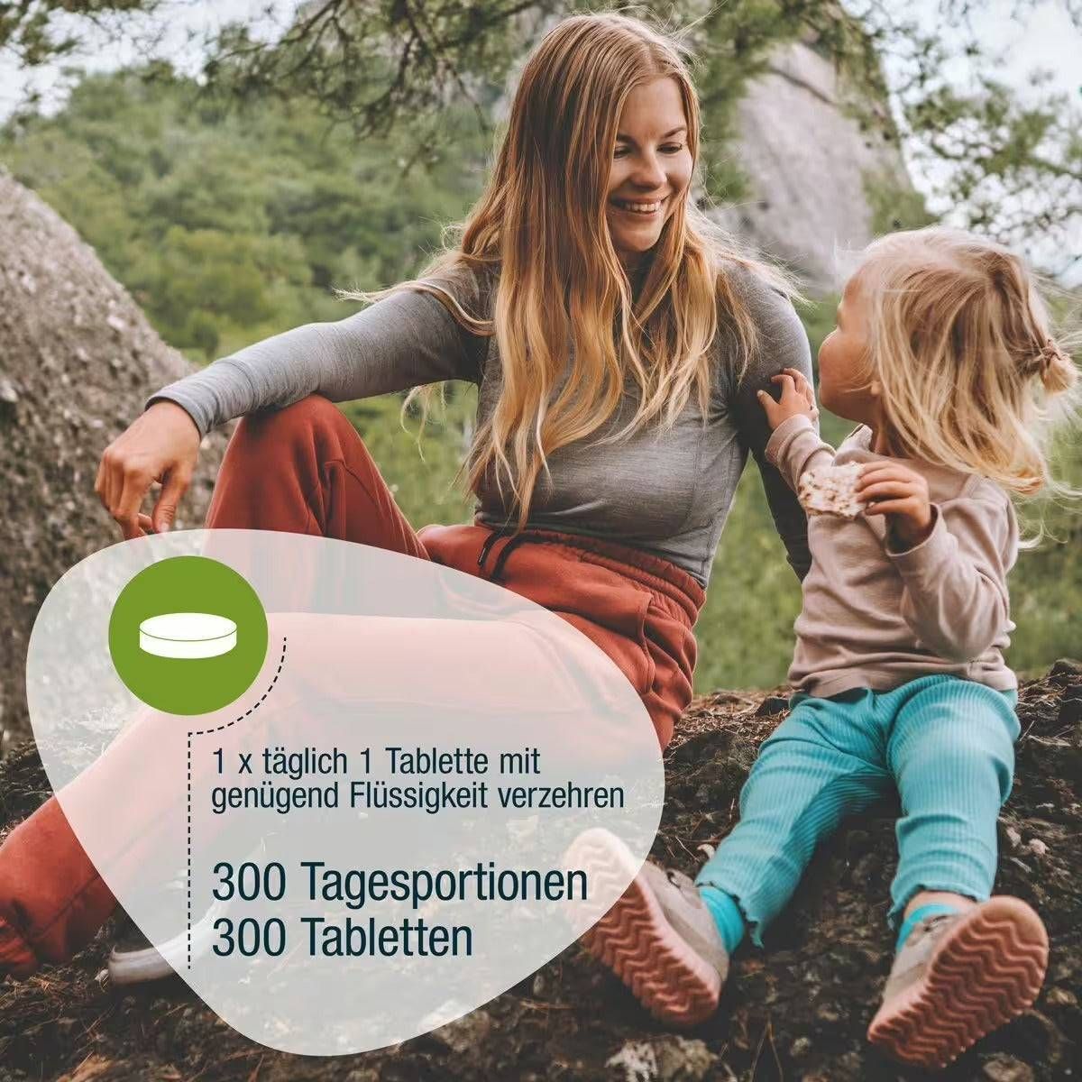 Eine Frau und ein Kind sitzen im Freien. Text: 1 Tablette täglich mit Flüssigkeit. 300 Tagesportionen, 300 Tabletten.