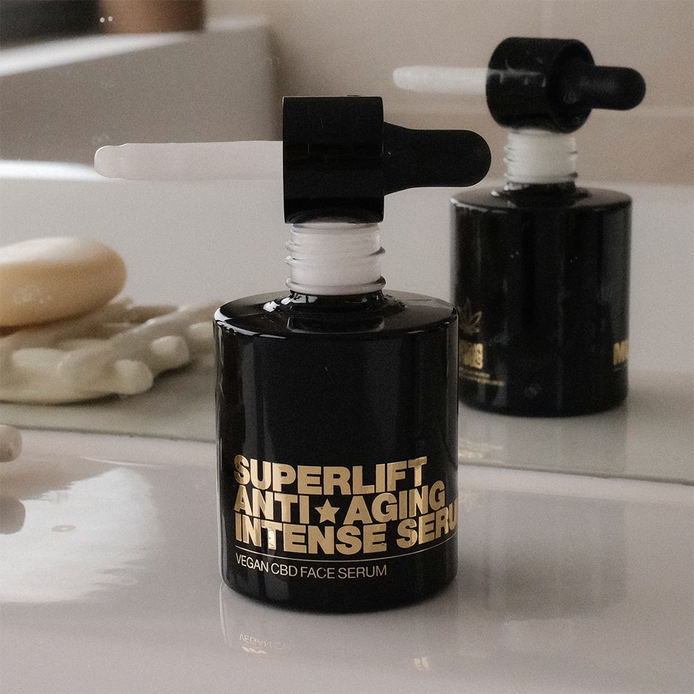 Schwarze Flasche mit goldfarbenem Text: Superlift Anti-Aging Intense Serum. Mit Pipette. Spiegelbild.